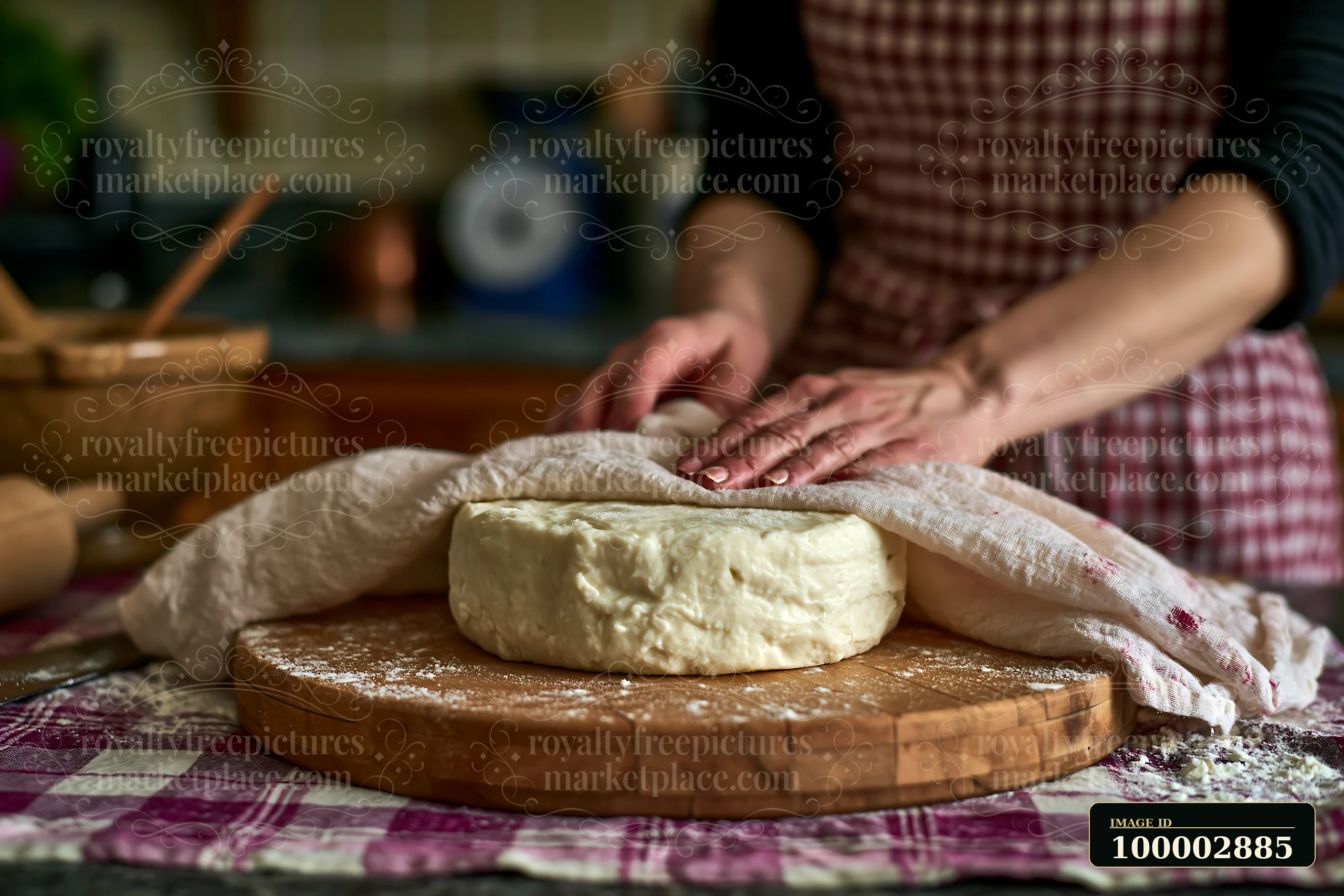 A baker presses dough with stained handmade linen on a wooden surface in a kitchen.