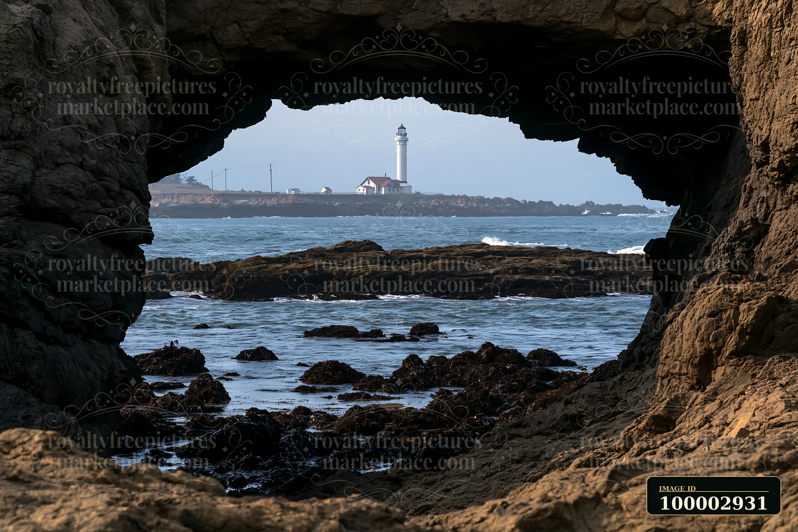 The coastline viewed through sea cave shows rocks and water as light filters through.