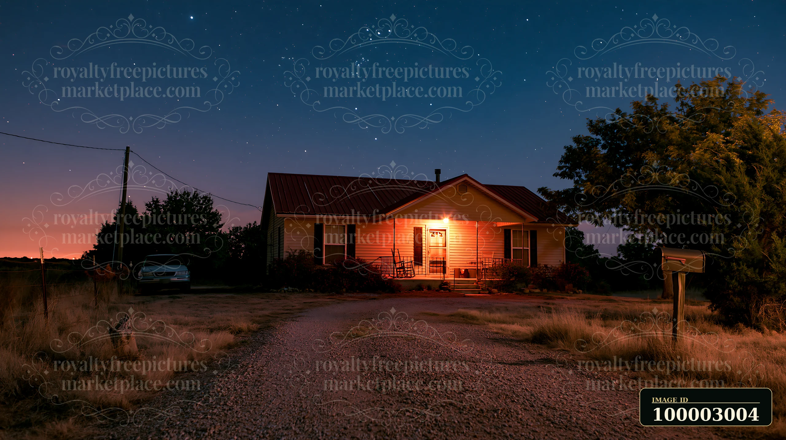 A warm light shines from a house under stars with gravel driveway, set in a rural area.