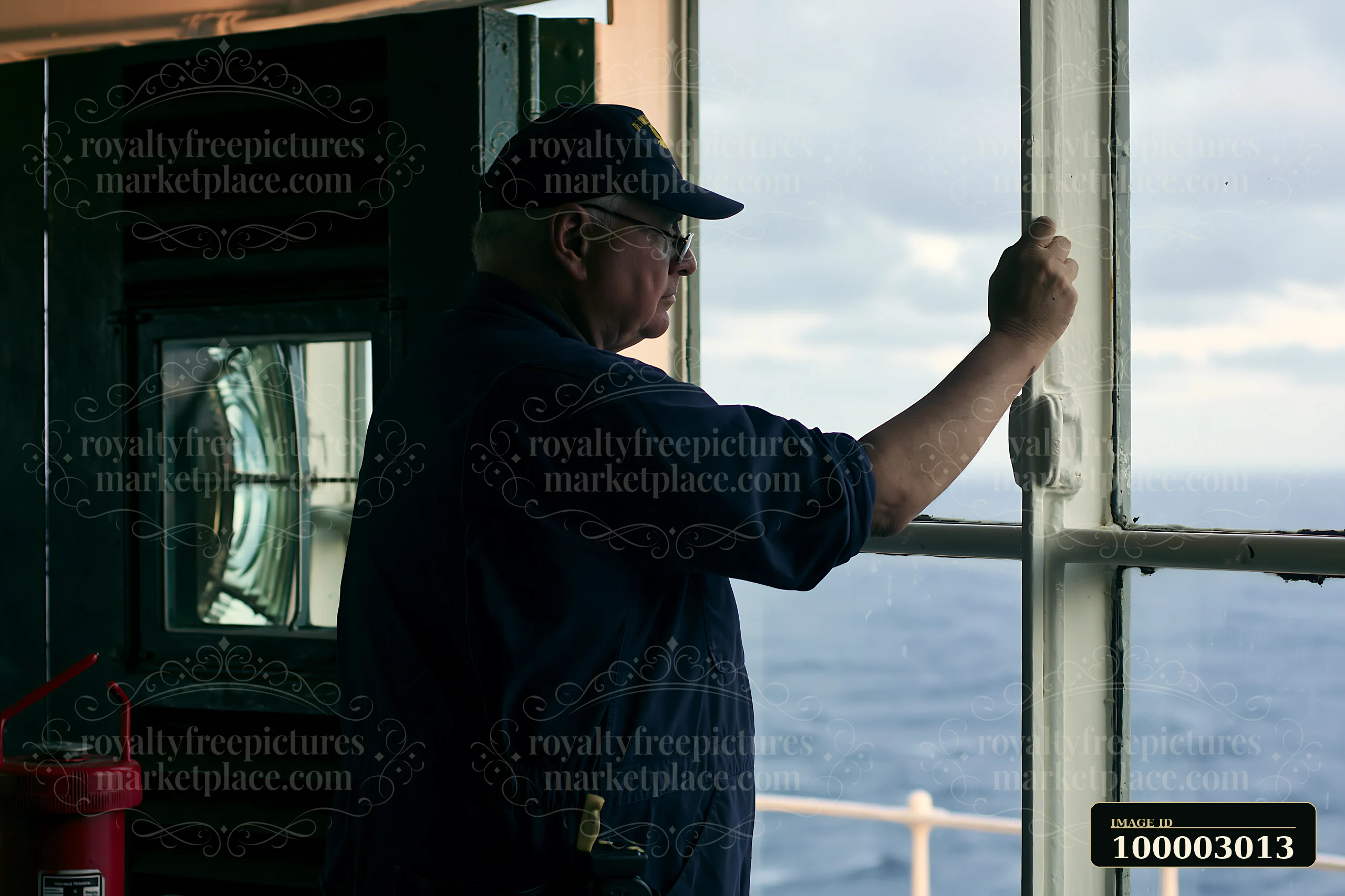 A lighthouse maintenance worker stands at a window, observing the view from the lighthouse tower.