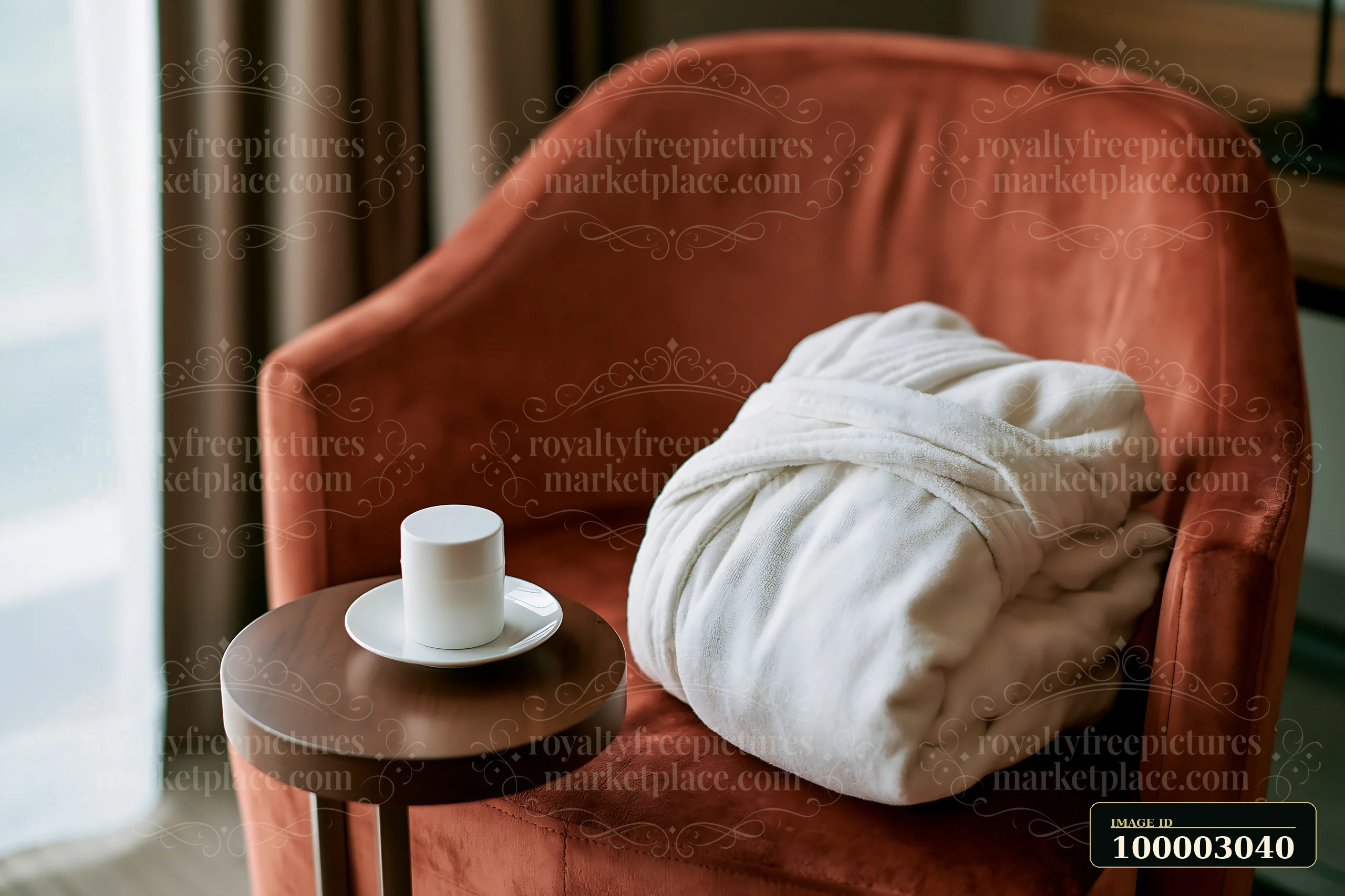 A white coffee cup sits on a small table beside a folded robe resting on a plush chair.