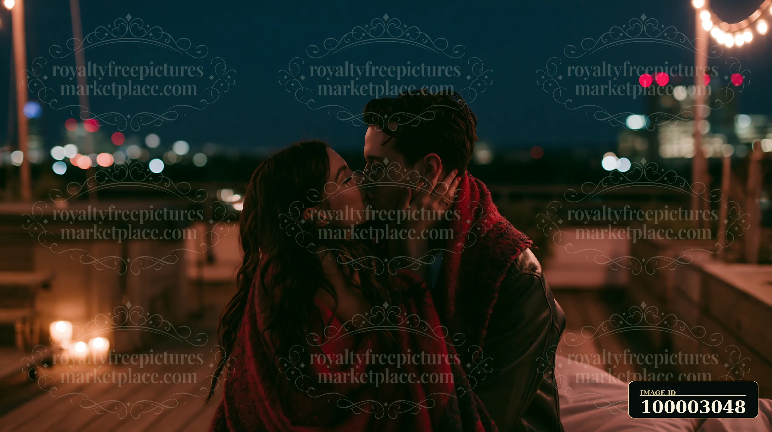 A couple kissing beneath stars while wrapped in blanket on a rooftop.