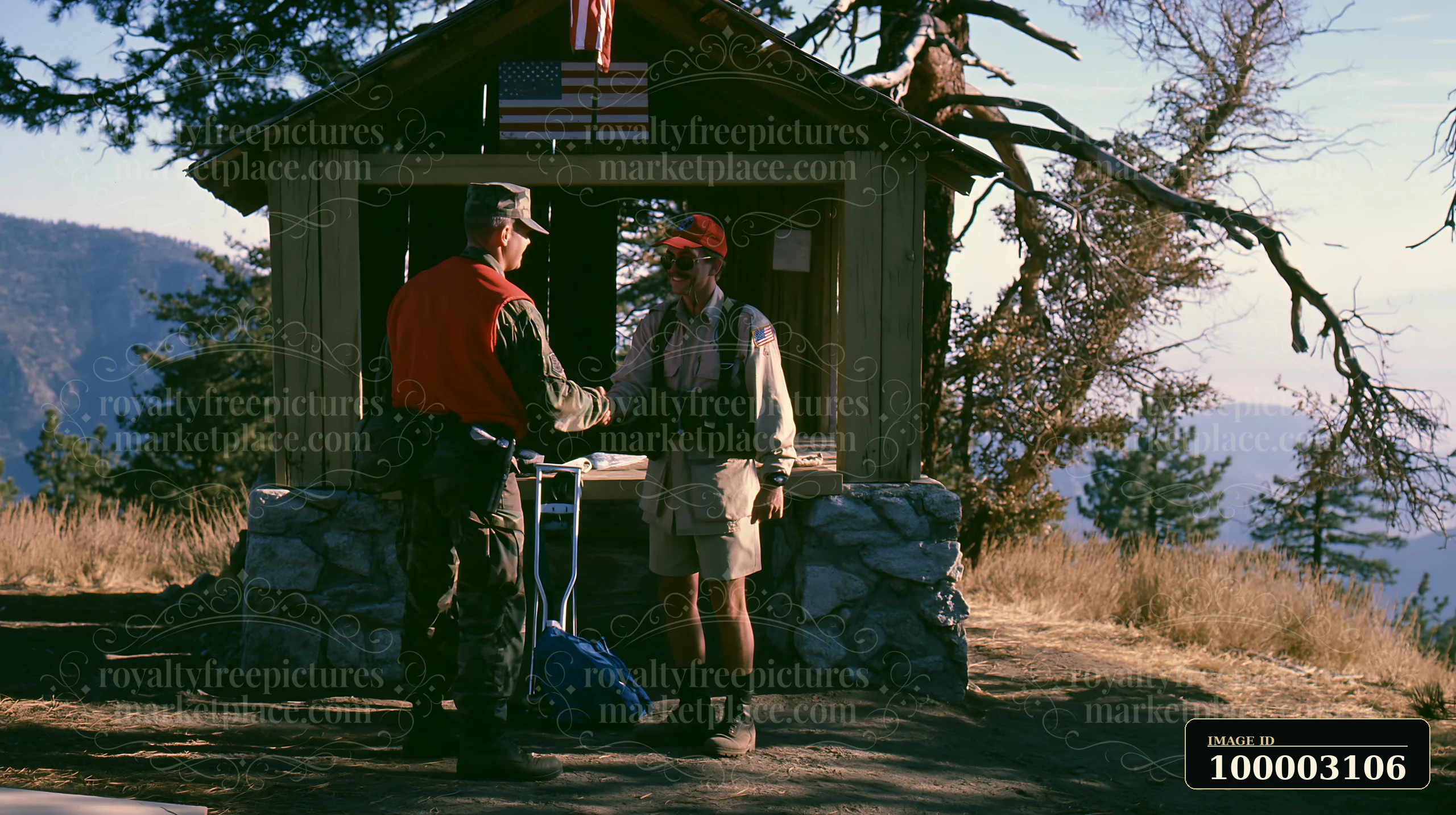 A soldier shaking hands with a hiker at a remote outdoor station in a forested area during daylight.