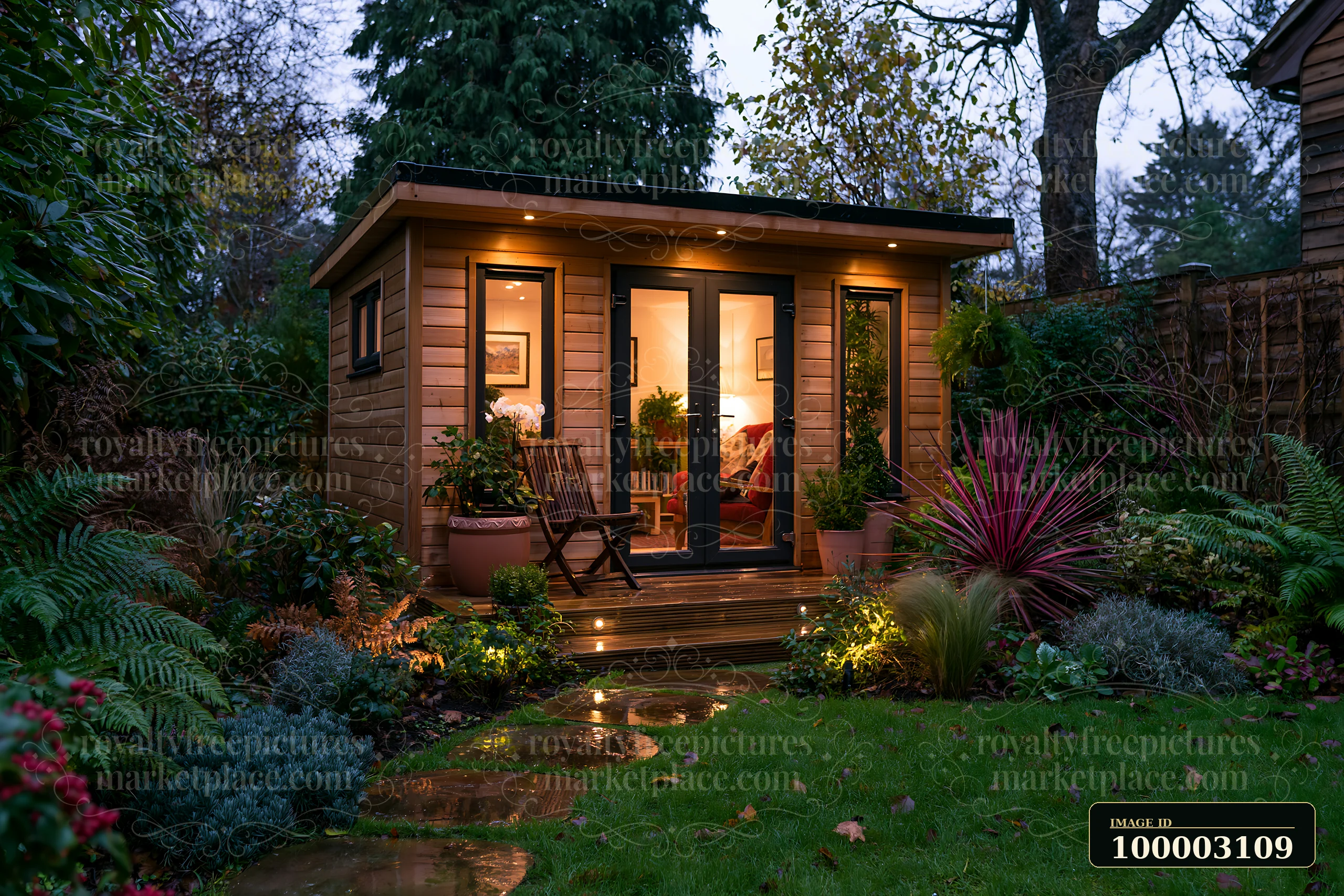 The garden studio features warm illumination at the entrance, surrounded by lush greenery and plants.