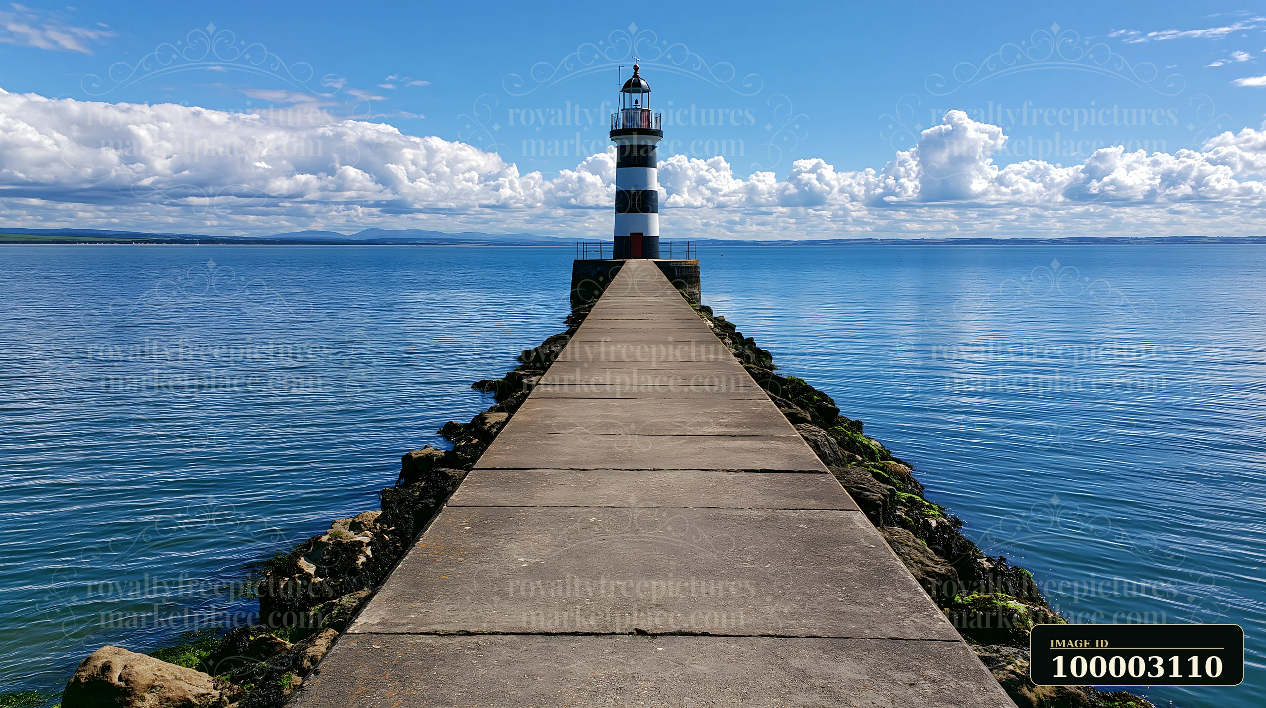A lighthouse with black and white stripes stands at the end of a pier, surrounded by calm water and blue skies.