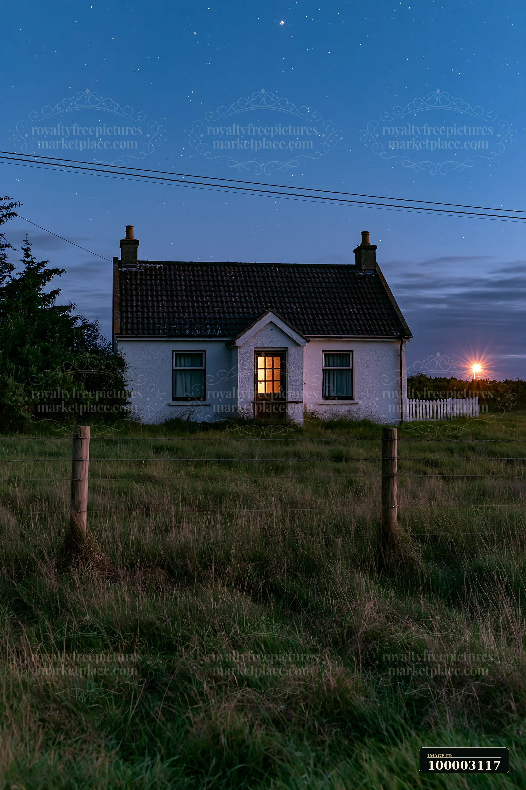 A small house stands alone in a meadow at night.