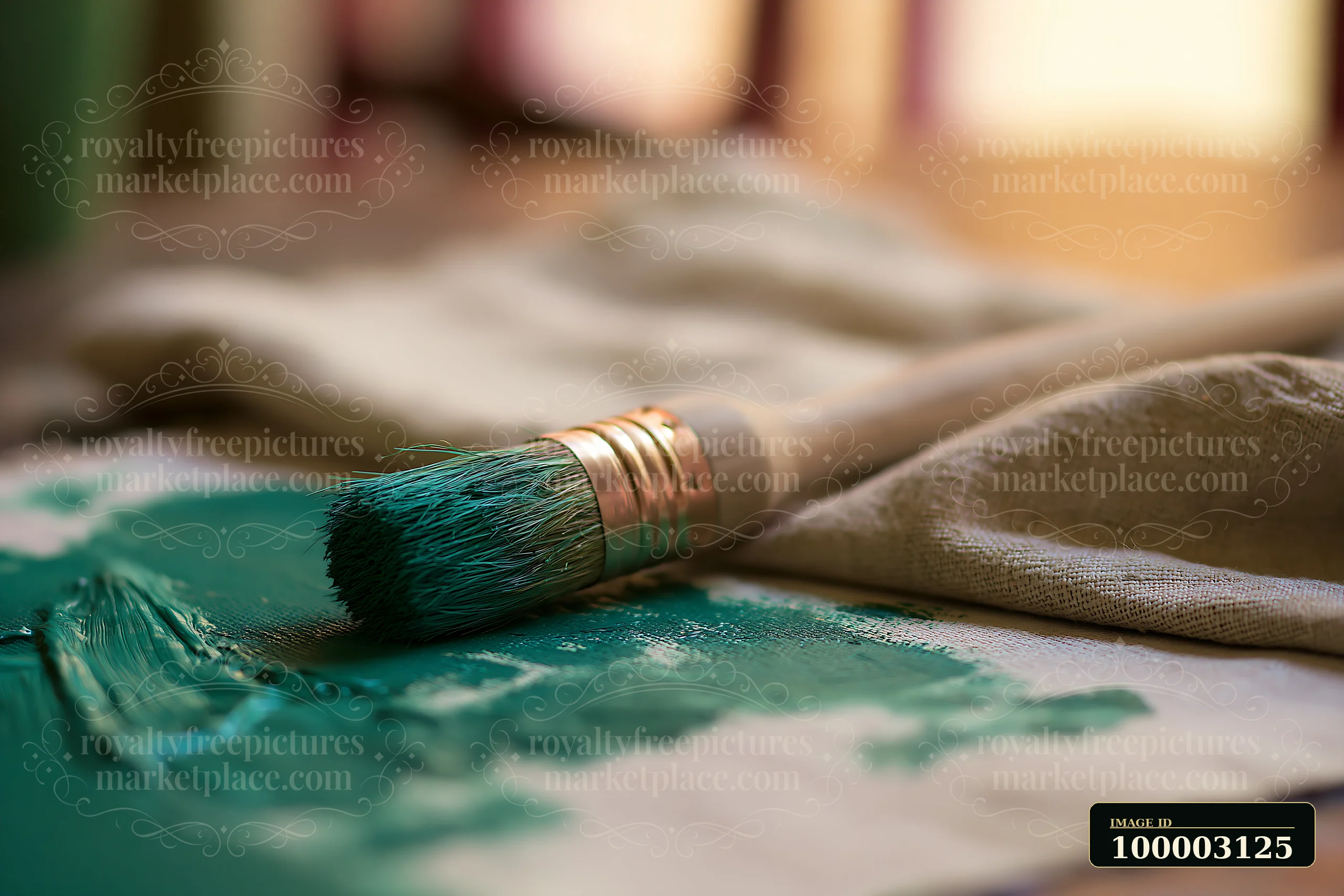 A paintbrush lies on canvas cloth with smears of green oil paint.