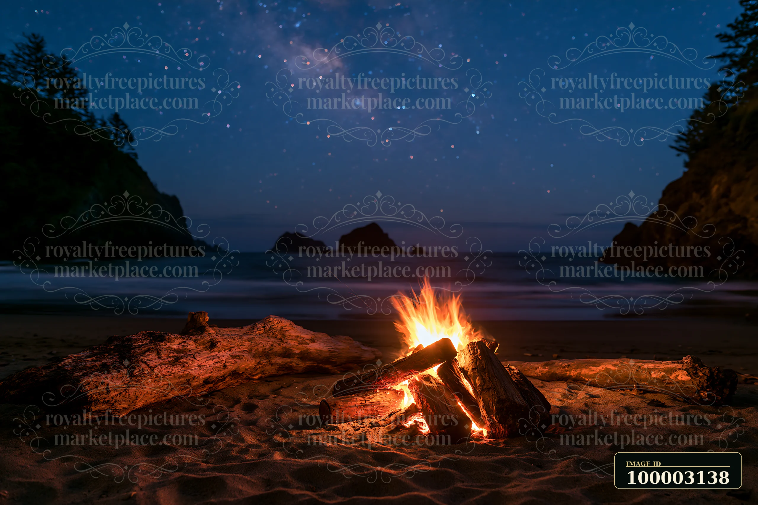 A campfire burns brightly on a sandy beach under a starry sky.
