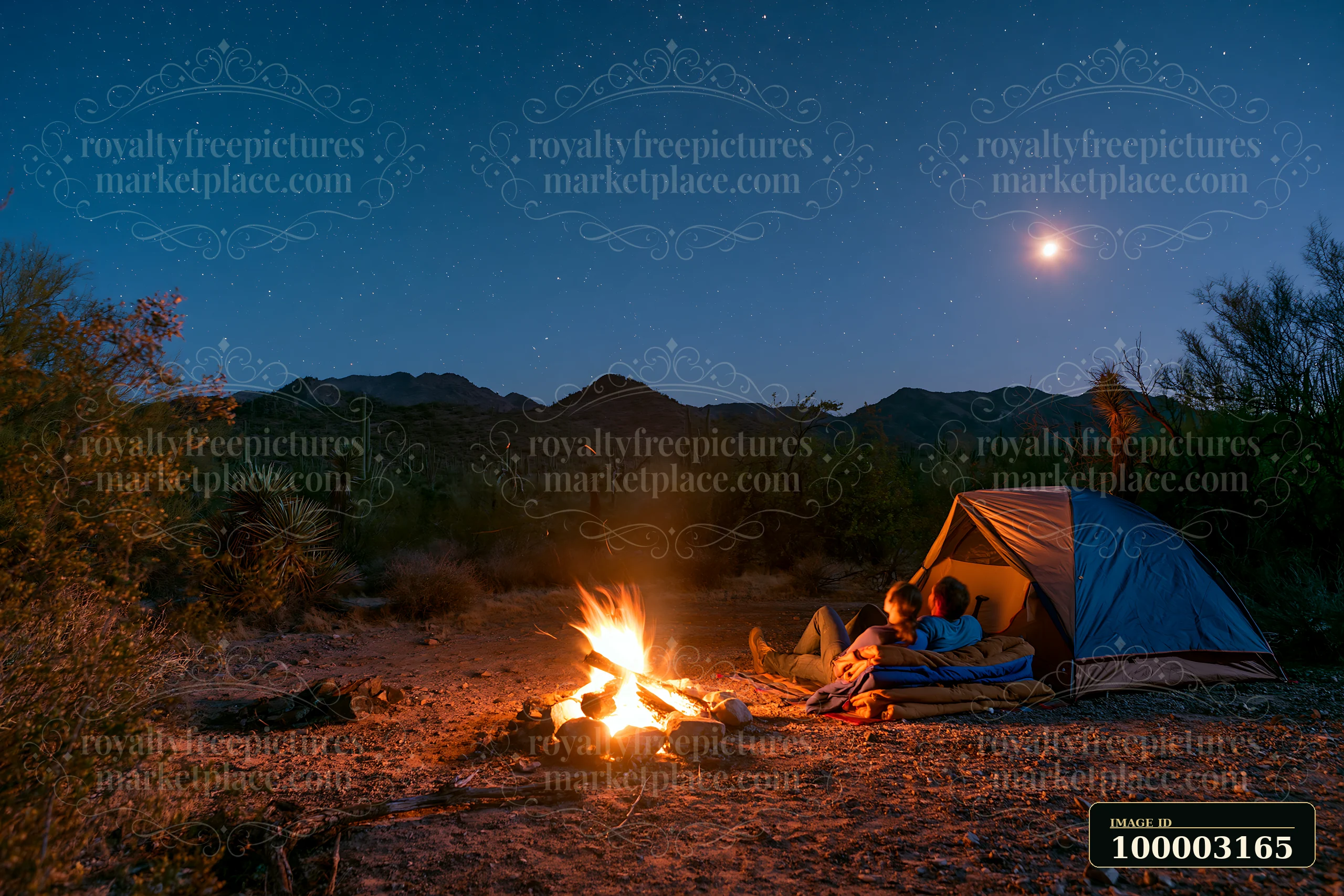 A couple sitting beside a glowing campfire under stars in a desert setting.