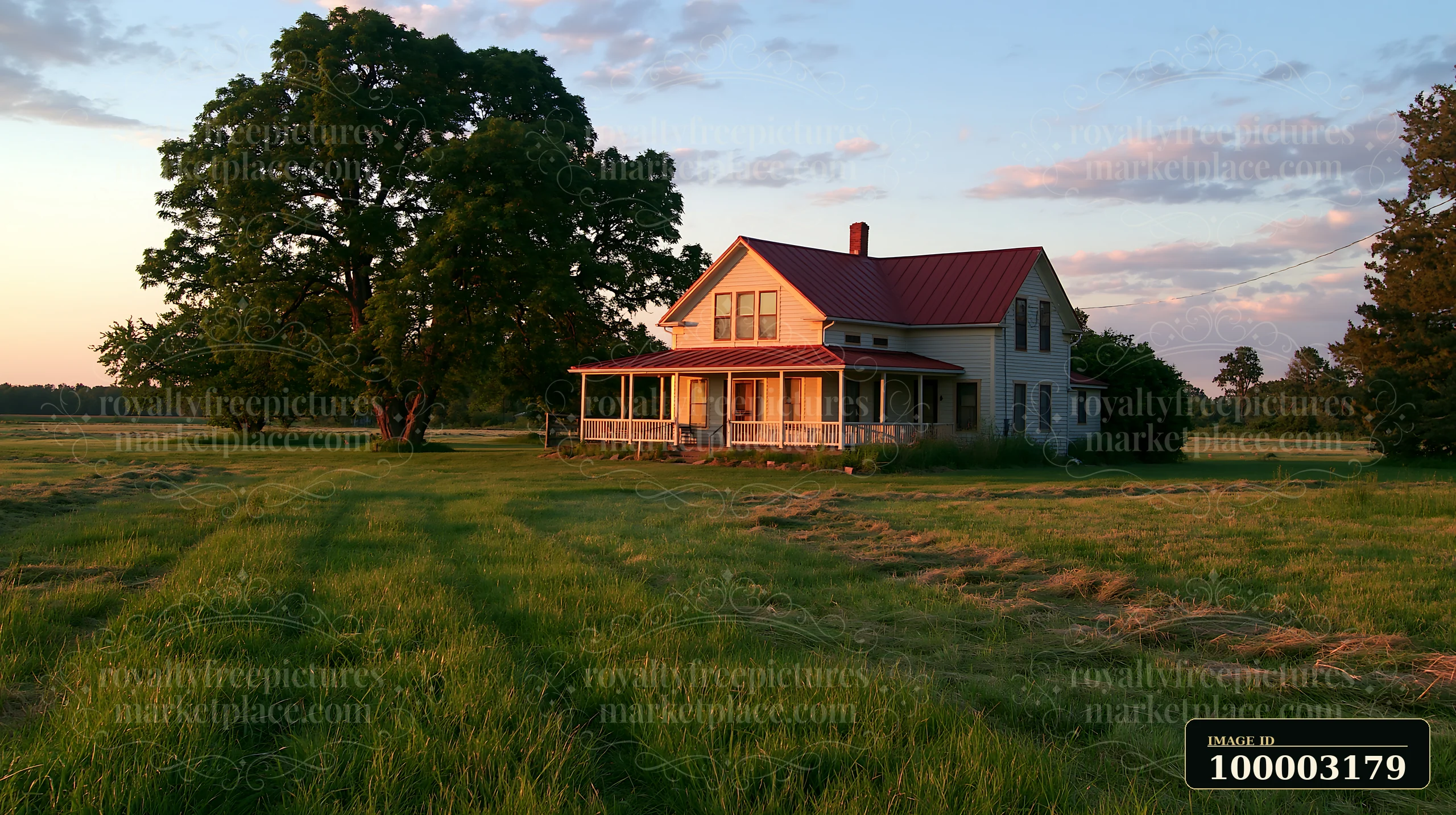 A restored farmhouse exterior stands in a wide field during sunset.