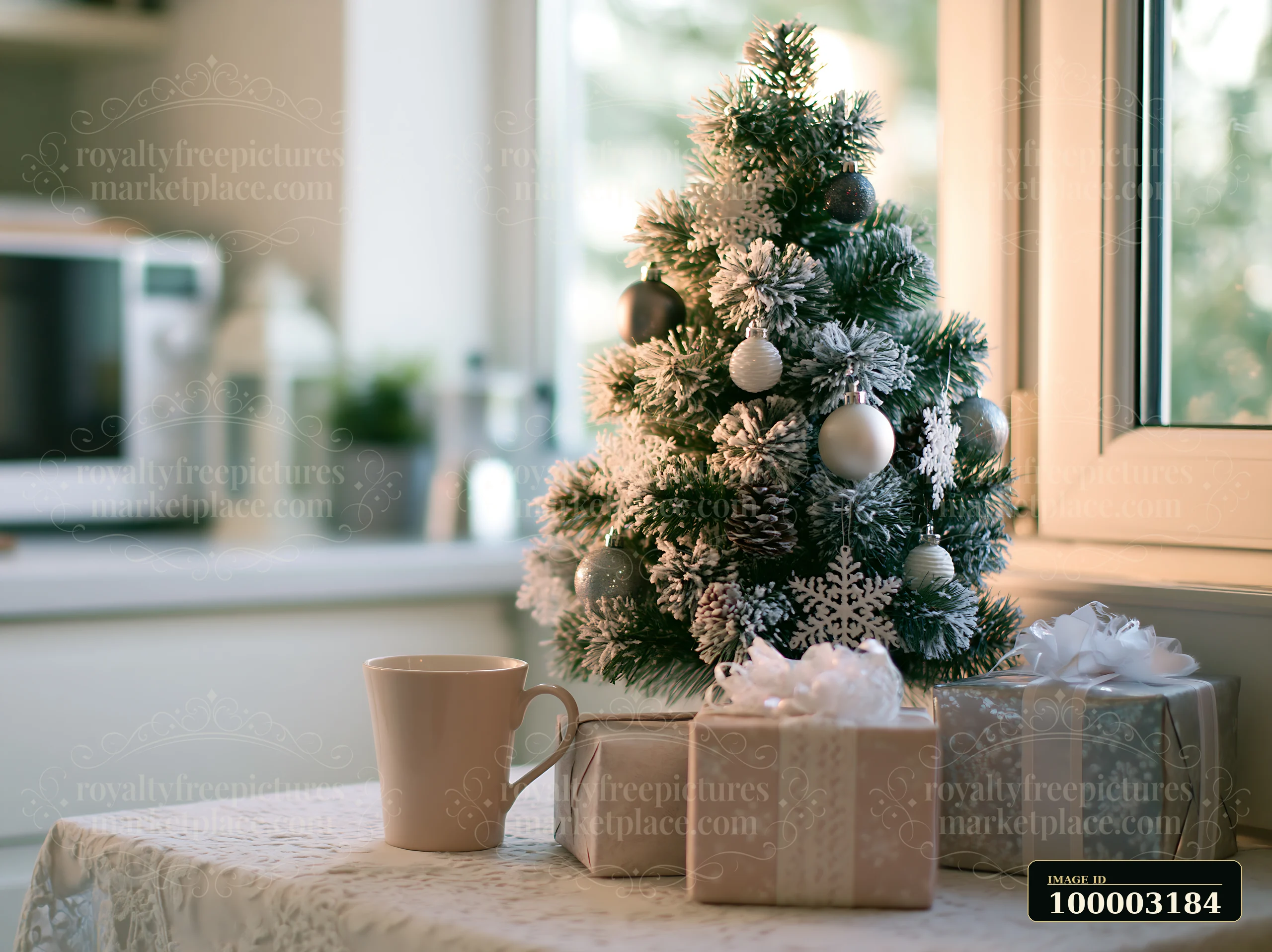 A Christmas tree with monochrome decorations stands on a table next to gift boxes and a cup.