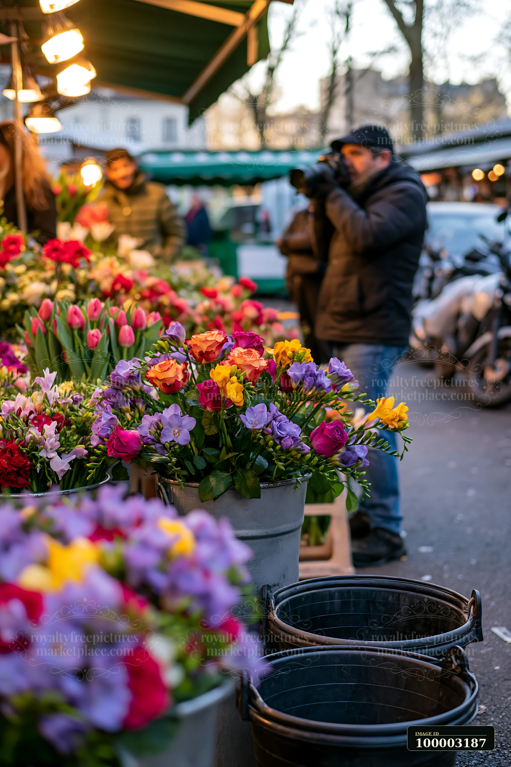 A street photographer taking pictures in an urban market focuses on the vibrant flowers.