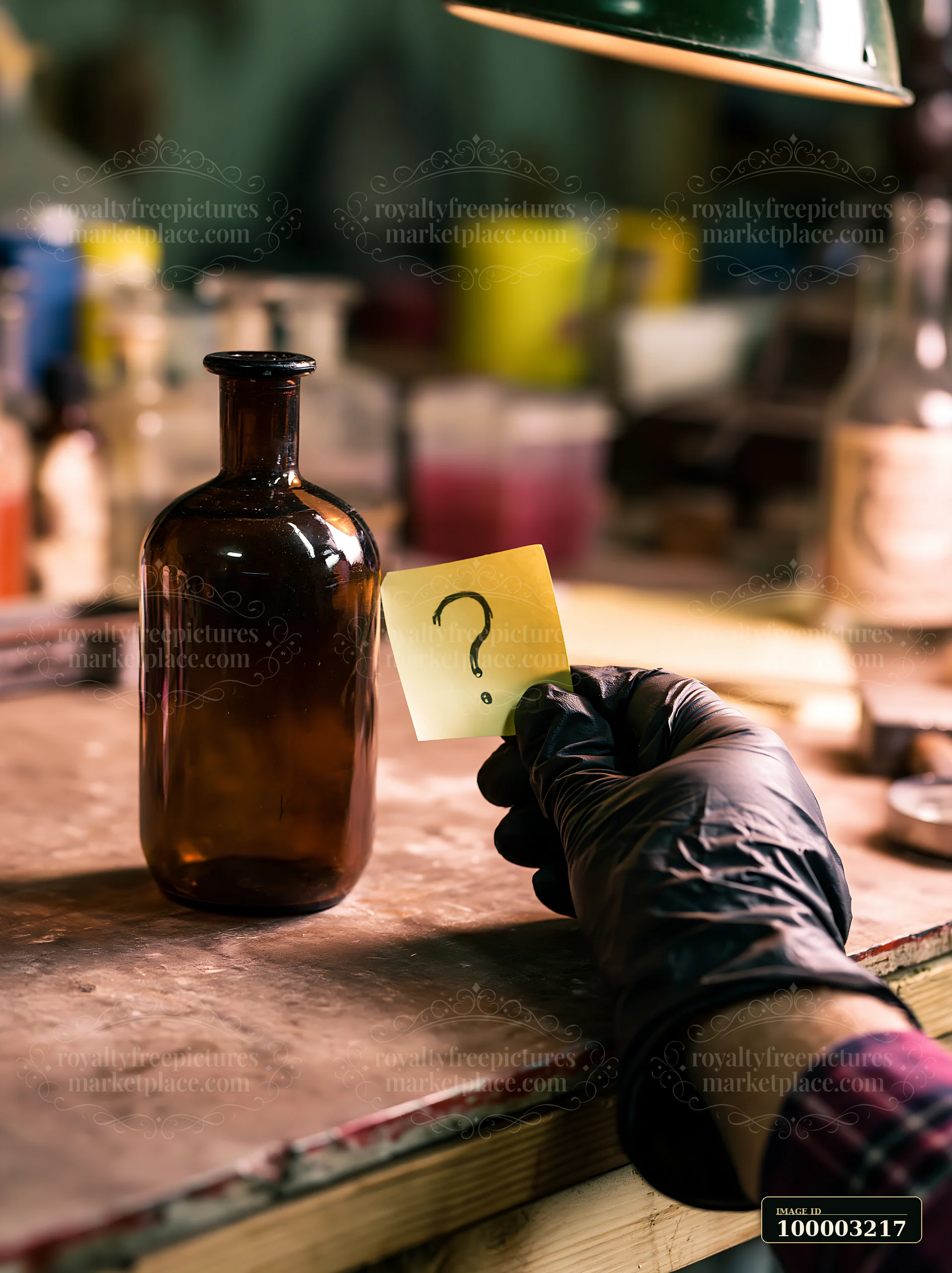 A person holds a note with a question mark next to an empty bottle on a wooden workbench.