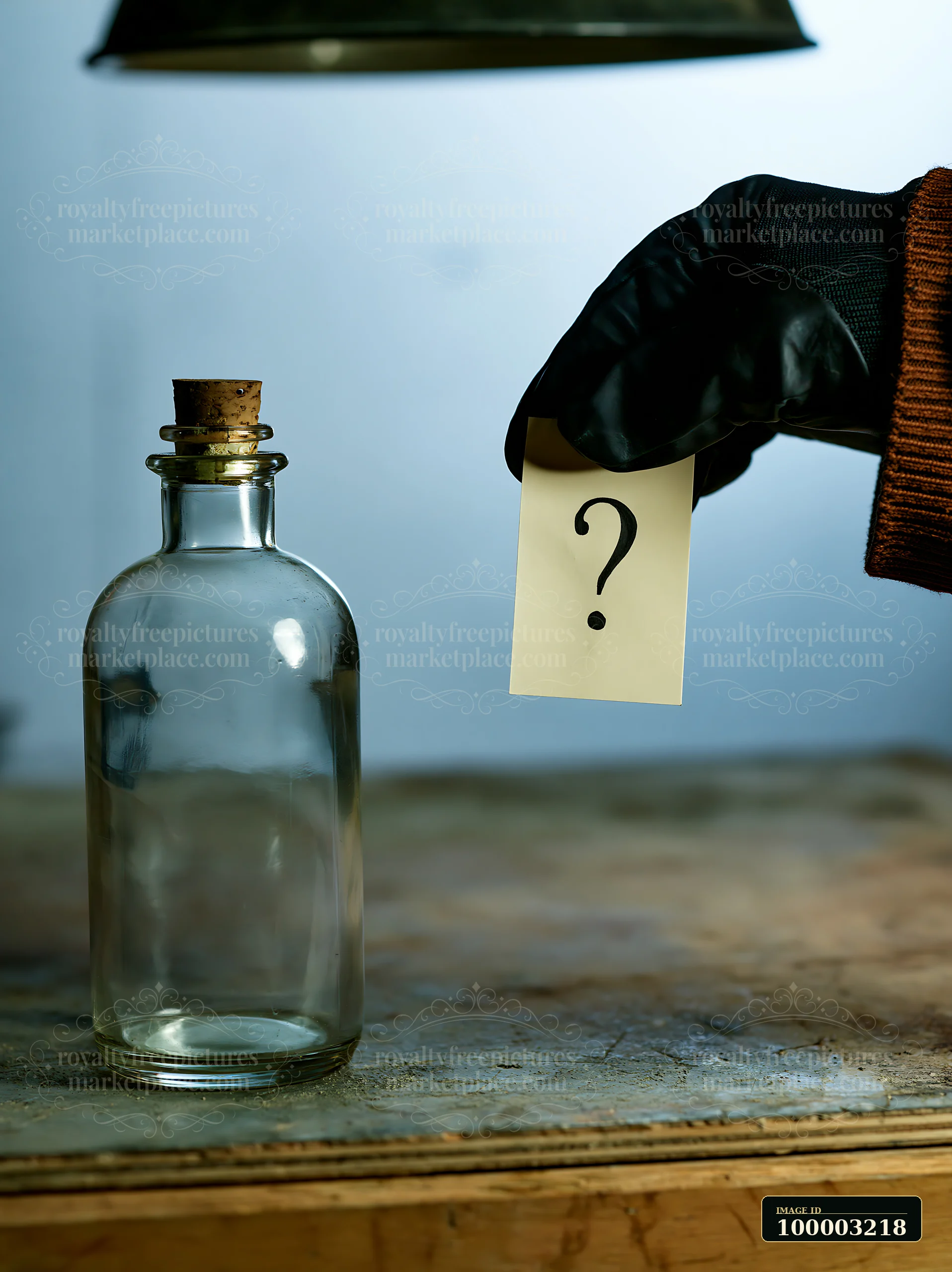 A hand in a black glove holds a note with a question mark next to an empty bottle on a wooden table.