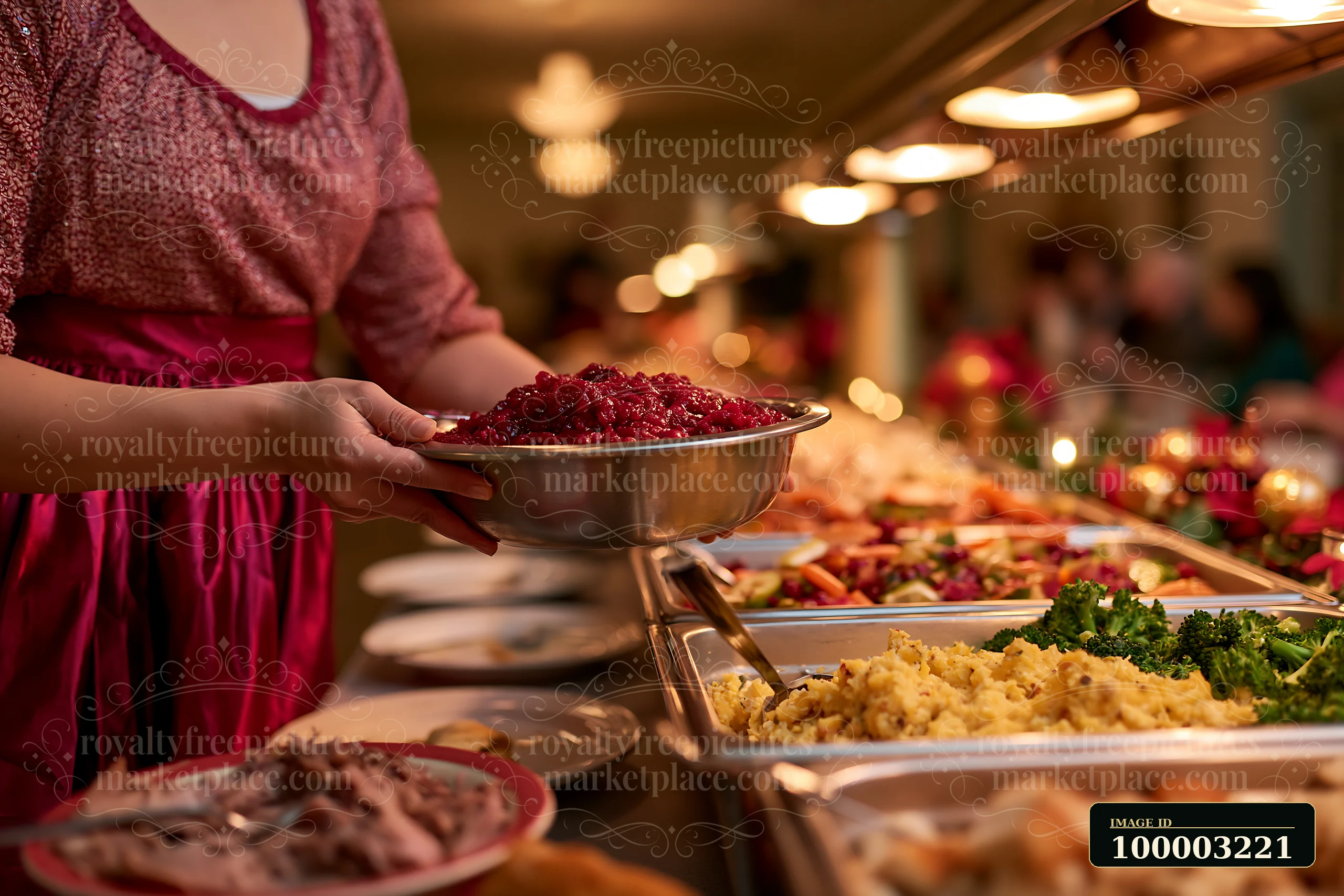 A person serves cranberry sauce from a bowl at a holiday buffet dinner in a warm setting.
