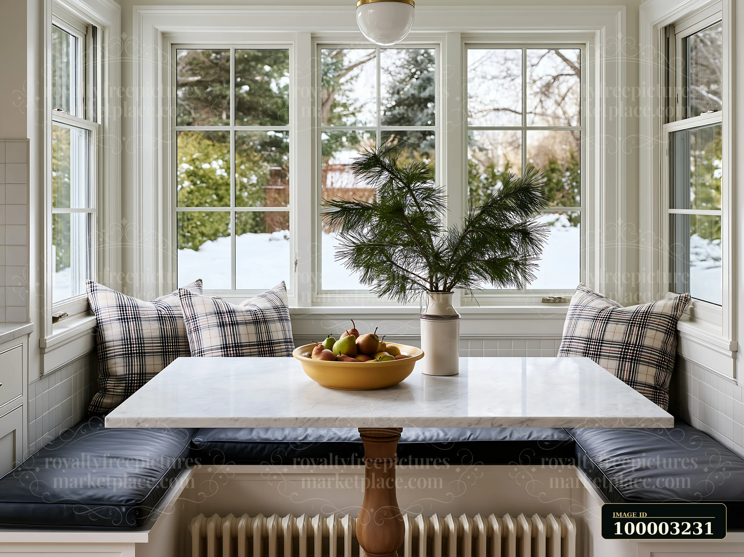 A cozy kitchen features a marble dining table with a bowl of fruits and a pine branch centerpiece.