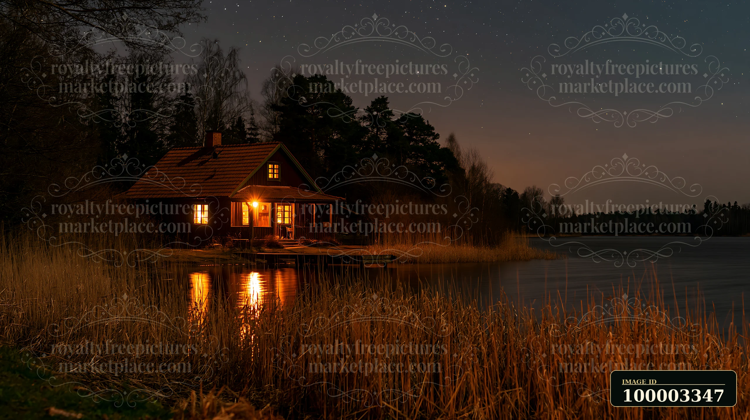 A warm-lit house stands by a lake, surrounded by trees and reeds.