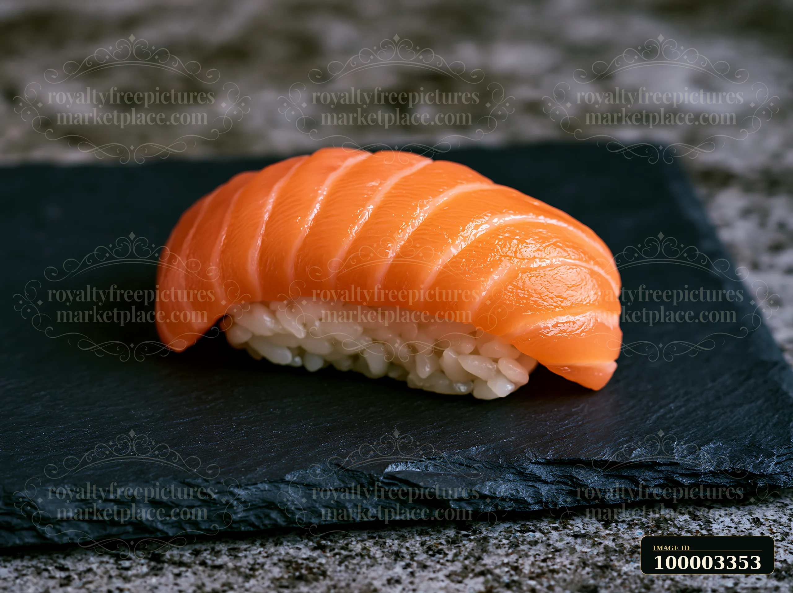 One salmon nigiri on slate plate shows a piece of sushi with slices of salmon on rice.