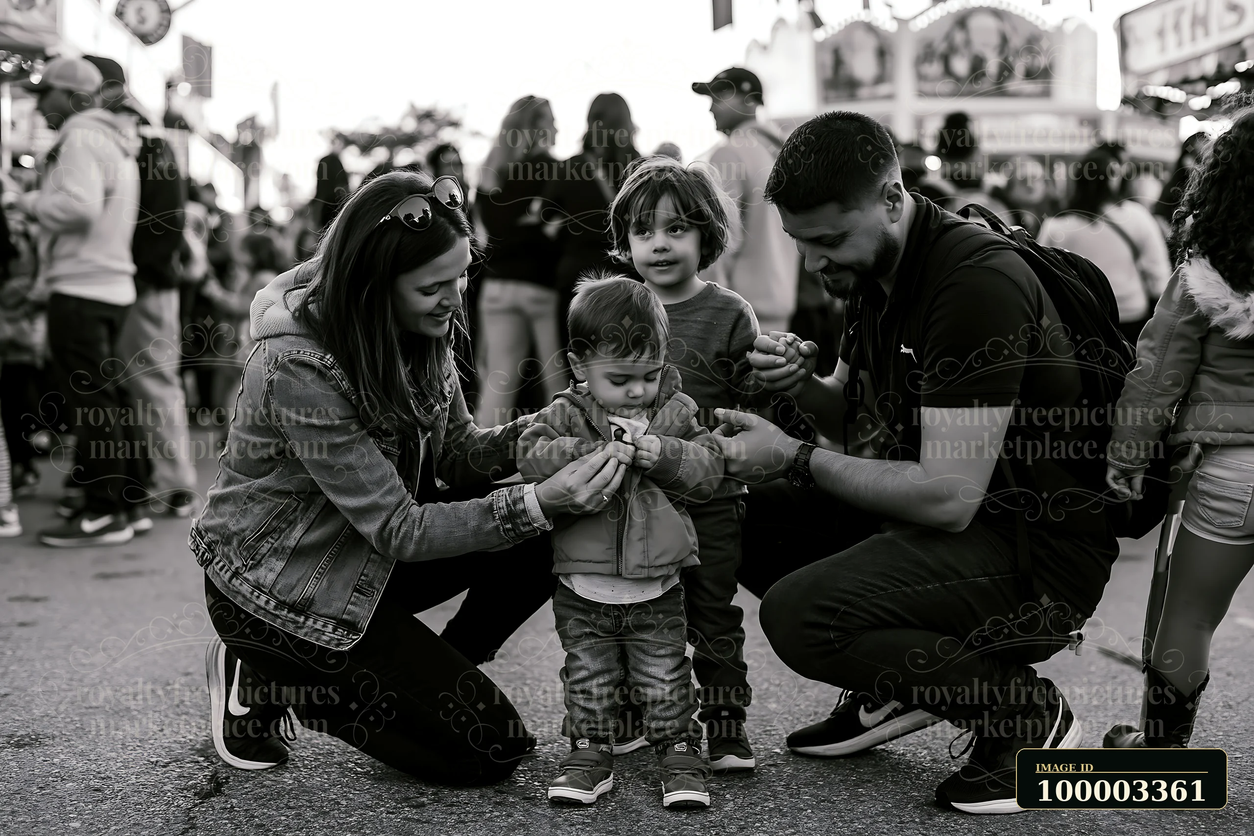Parents guide their two children through a busy carnival filled with people and attractions as they prepare for a fun day.