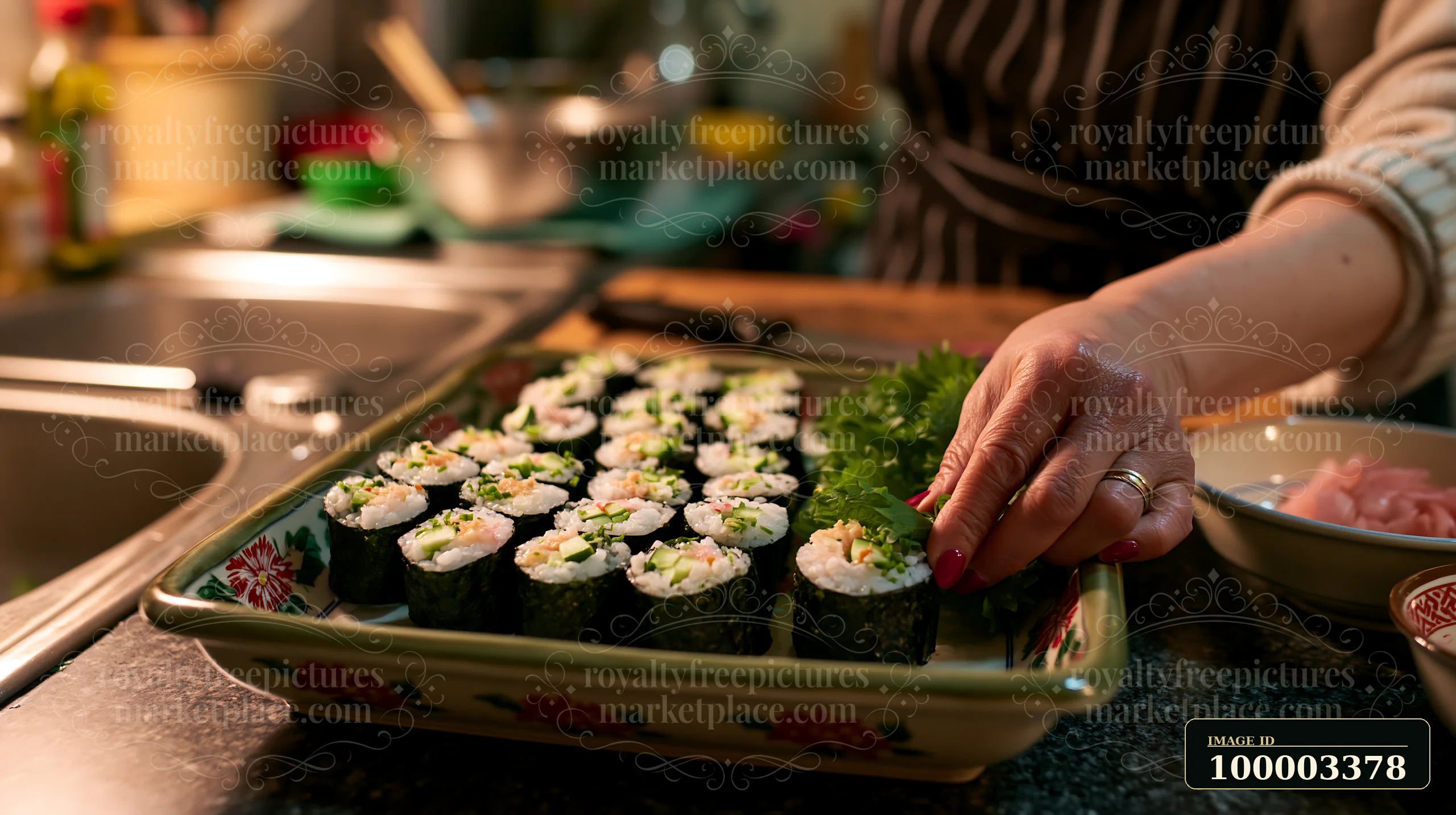 A person is carefully placing sushi with shiso leaves on a serving tray in a home kitchen.