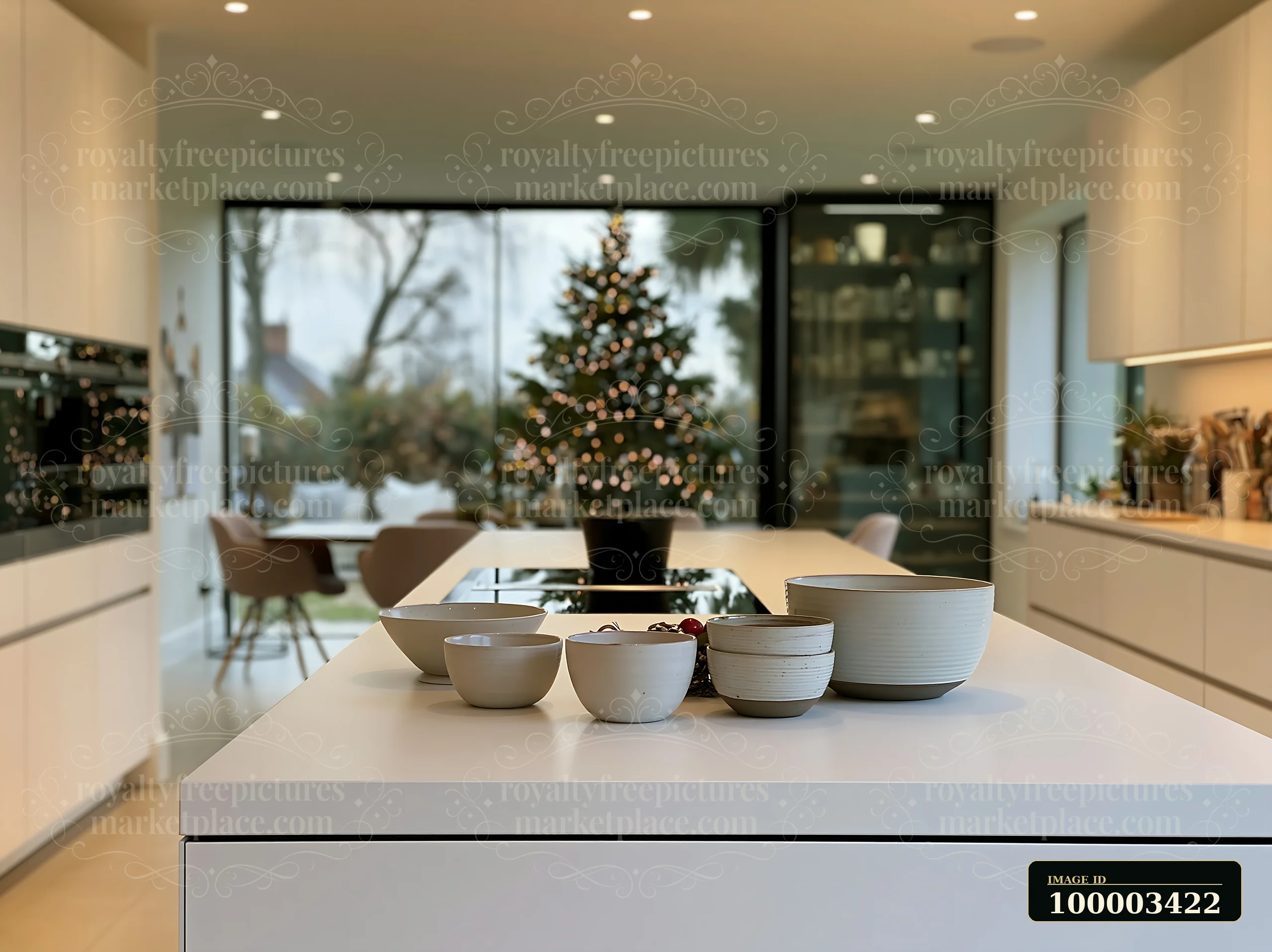 A modern kitchen features a sleek island with bowls and a view of a Christmas tree reflecting in the window.