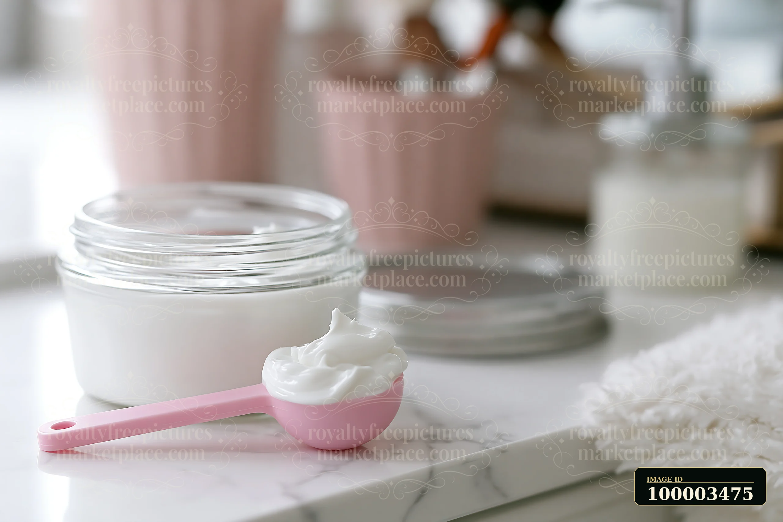 A cosmetic scoop holds a measured dose of cream next to a jar of the same cream on a bathroom counter.