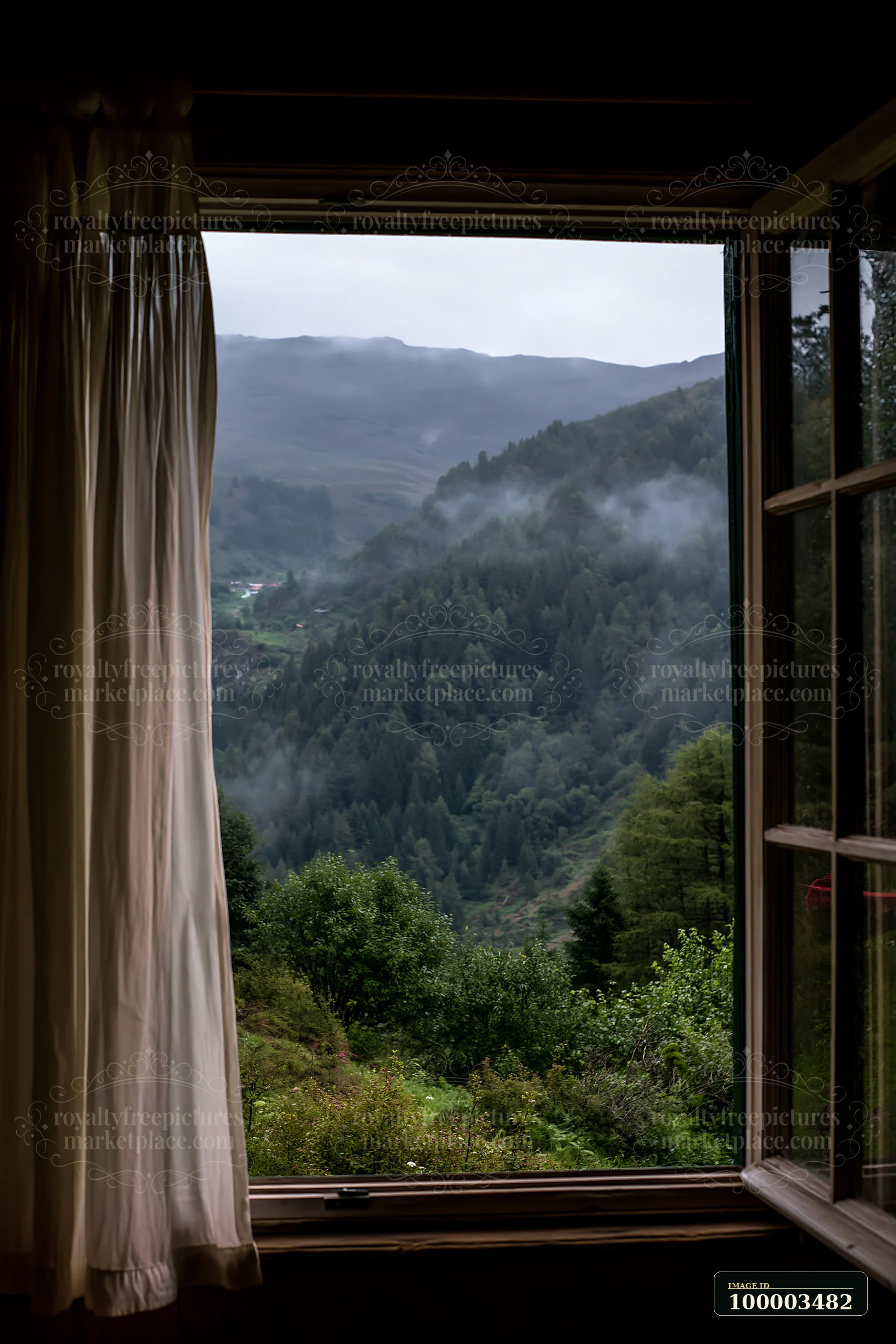Raindrops slide down a cabin window, revealing a mountain landscape with lush greenery and mist rolling over the hills.
