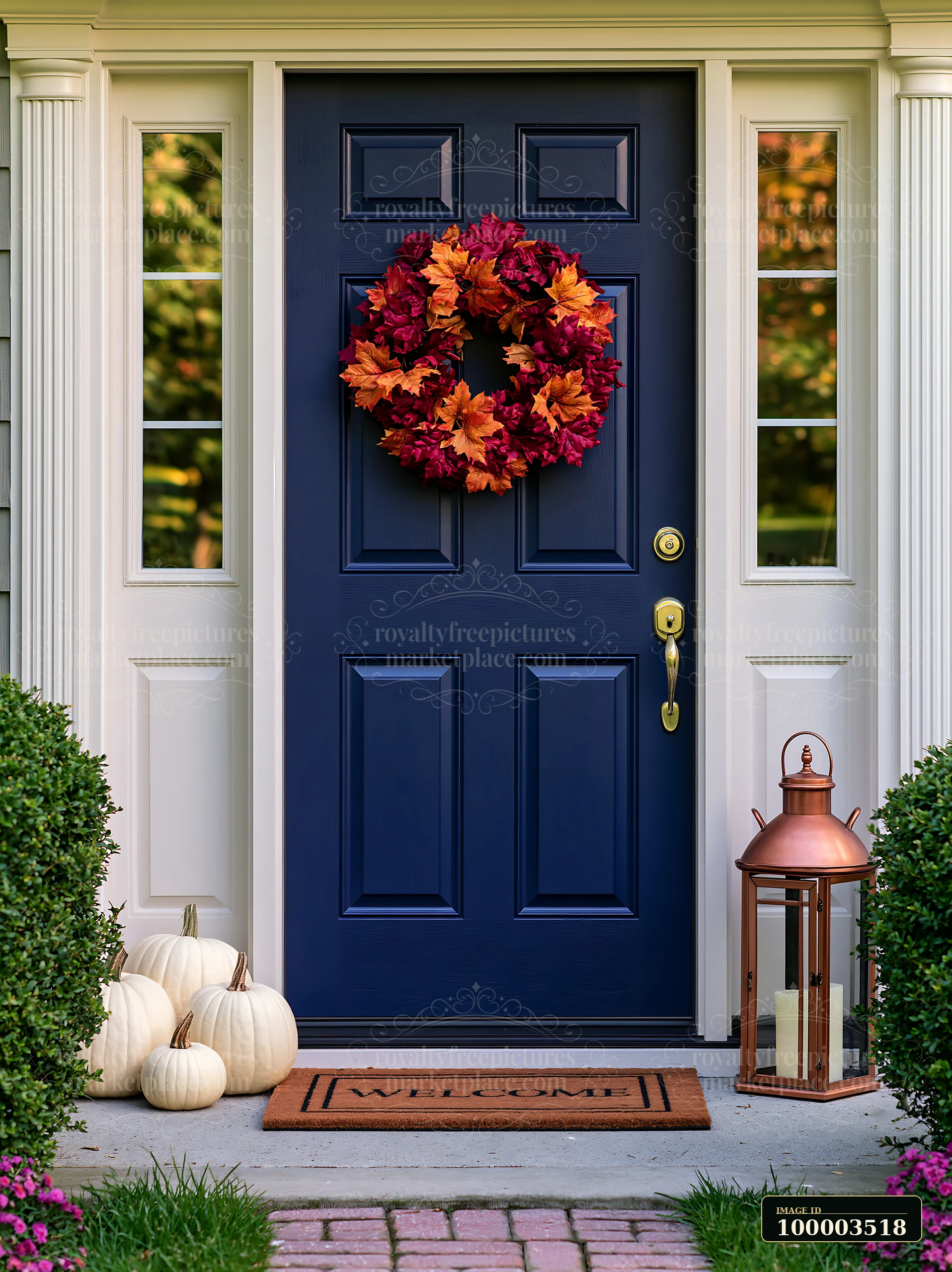 A front door with a colorful wreath, a welcome mat, and white pumpkins sits beside a lantern.