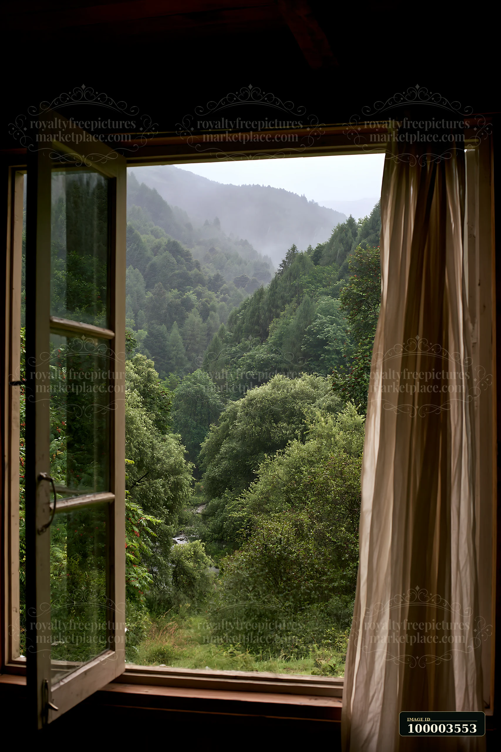 Raindrops fall on a cabin window, revealing a mountain landscape with dense green trees and mist covering the hills.