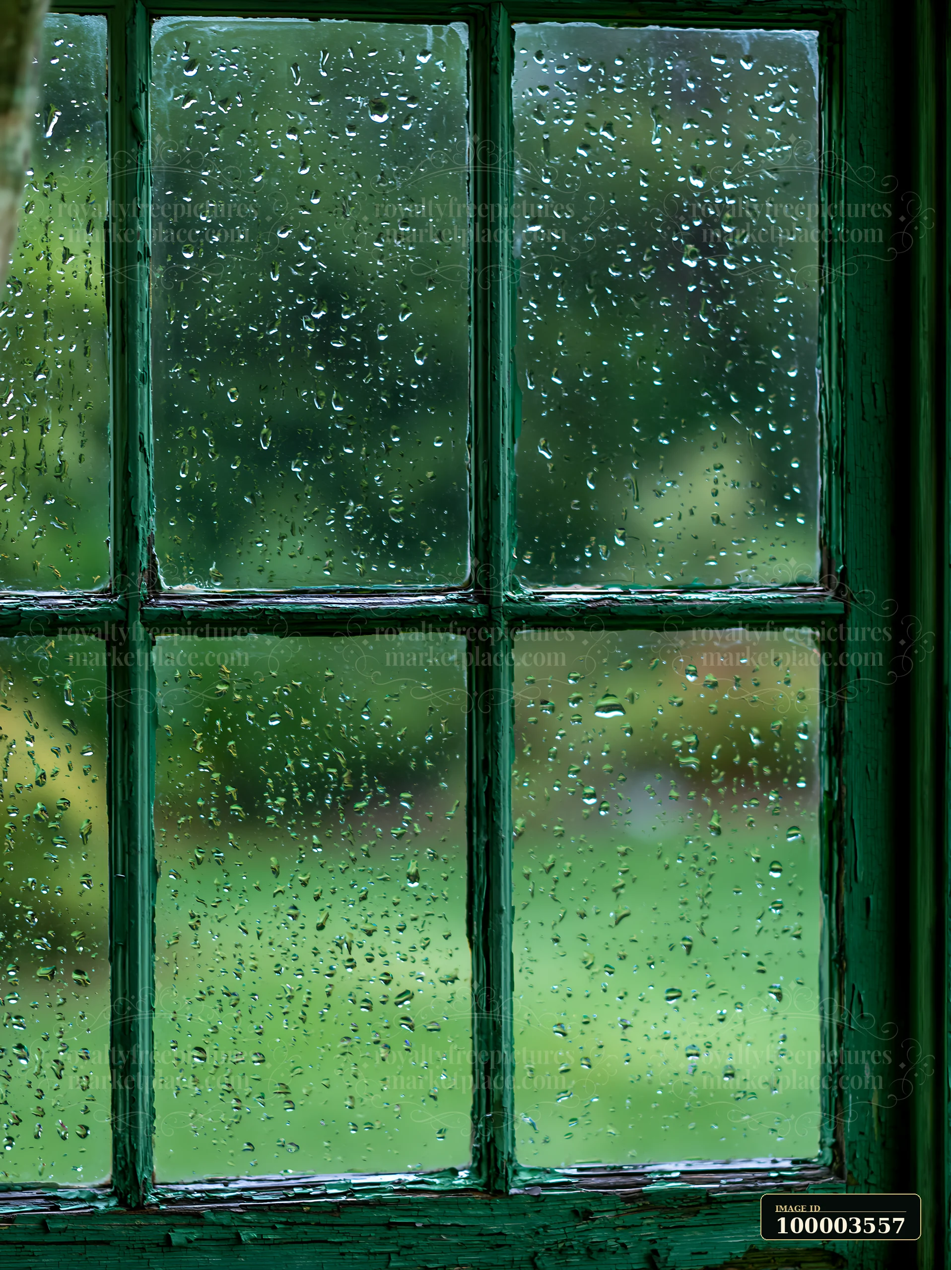 Raindrops collect on a rustic wooden window pane, providing a close-up rain texture on rustic window pane.