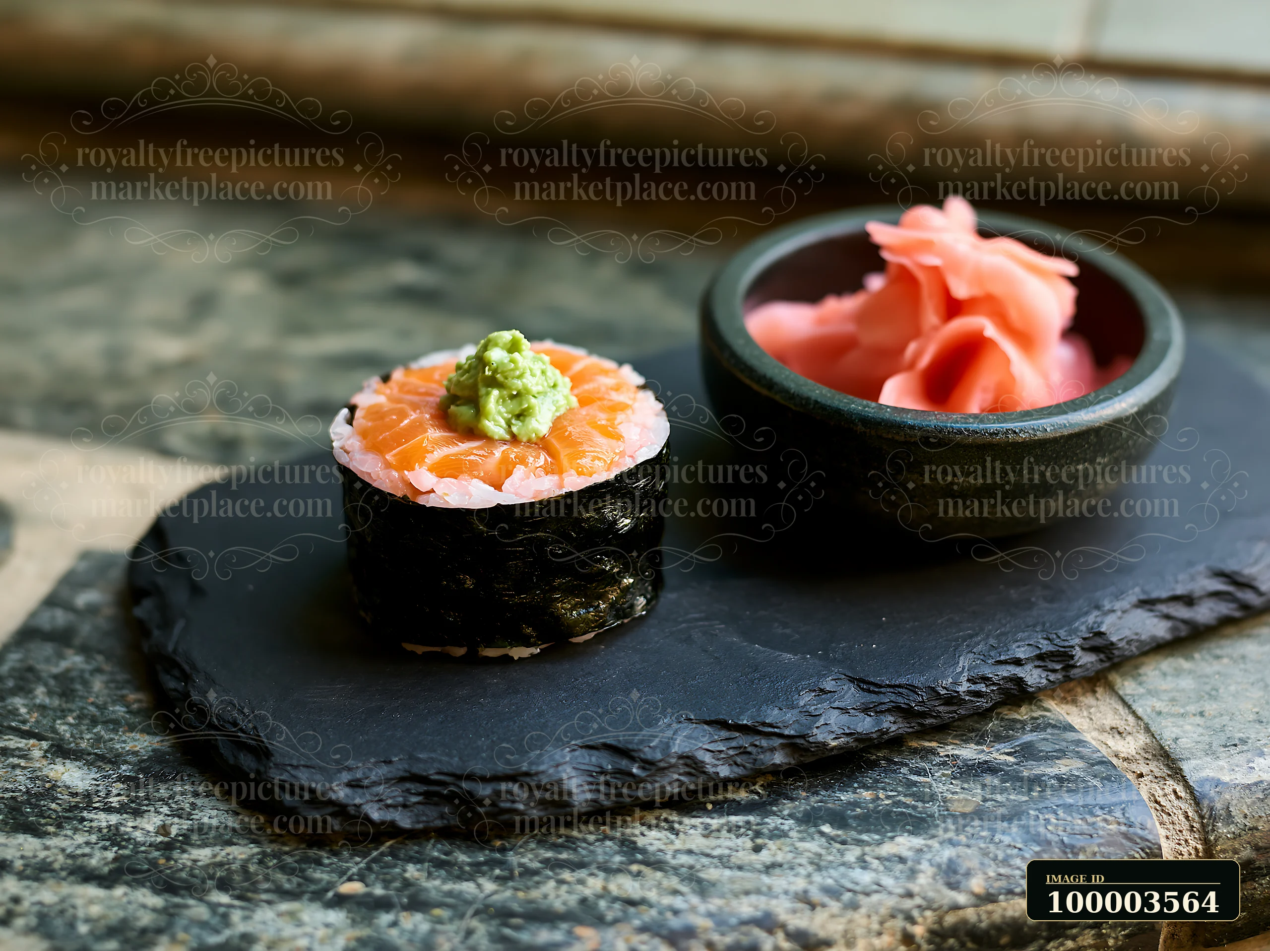 One salmon maki piece with wasabi sits on a dark slate plate beside a small bowl of pickled ginger.