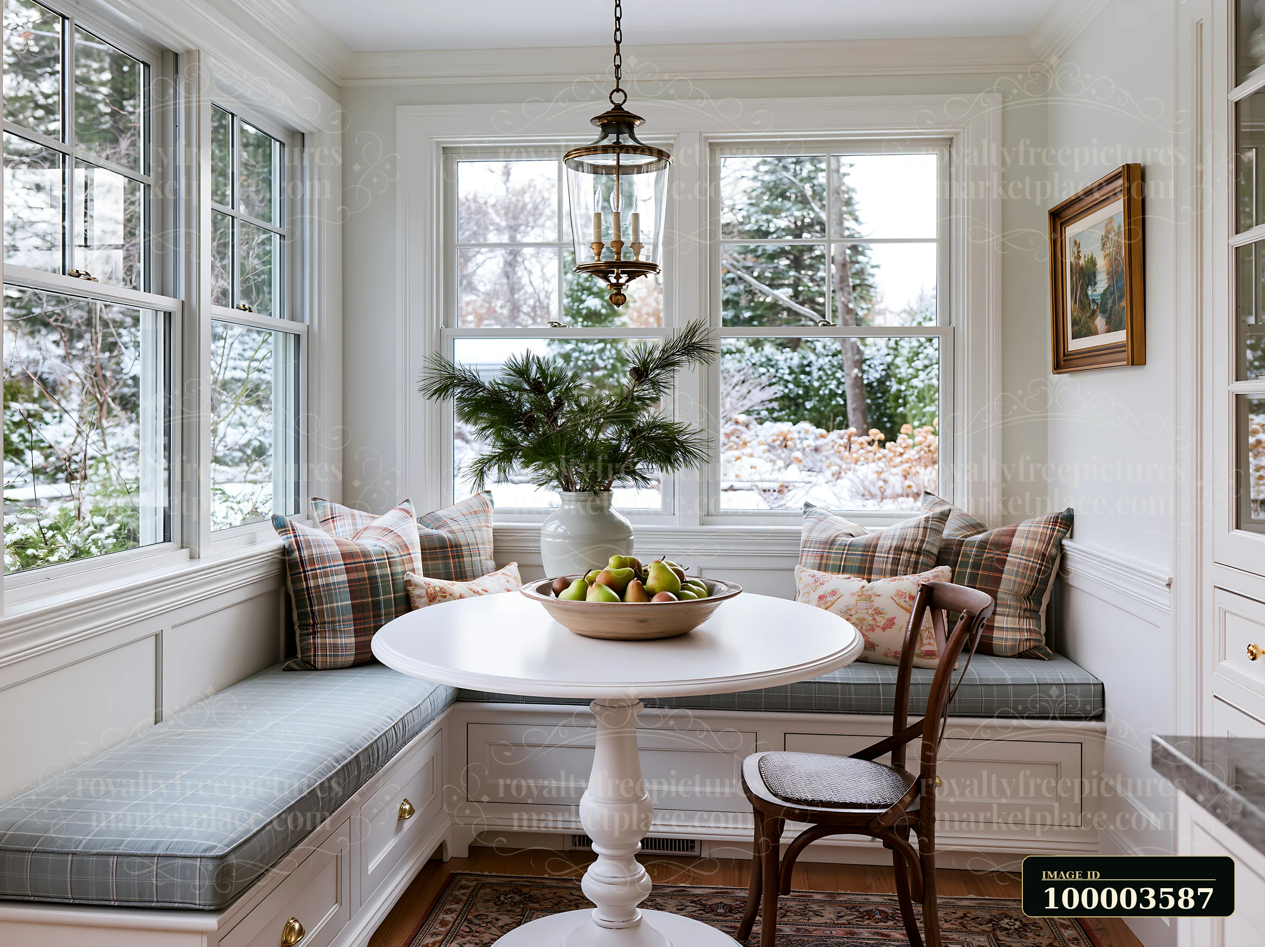 A cozy kitchen features a round table and a window seat with decorative pillows.