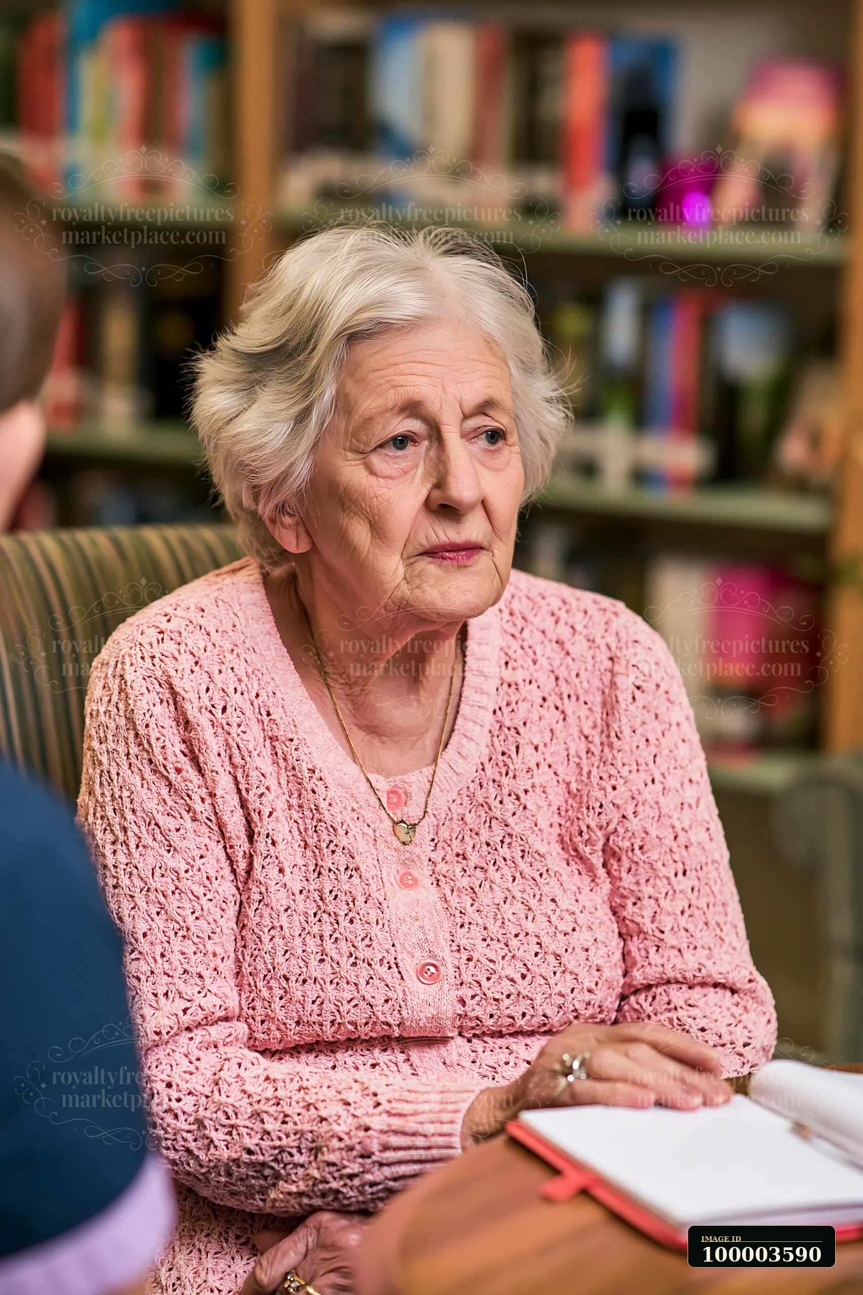 A senior woman with dementia listening to a caregiver while seated in a comfortable chair.