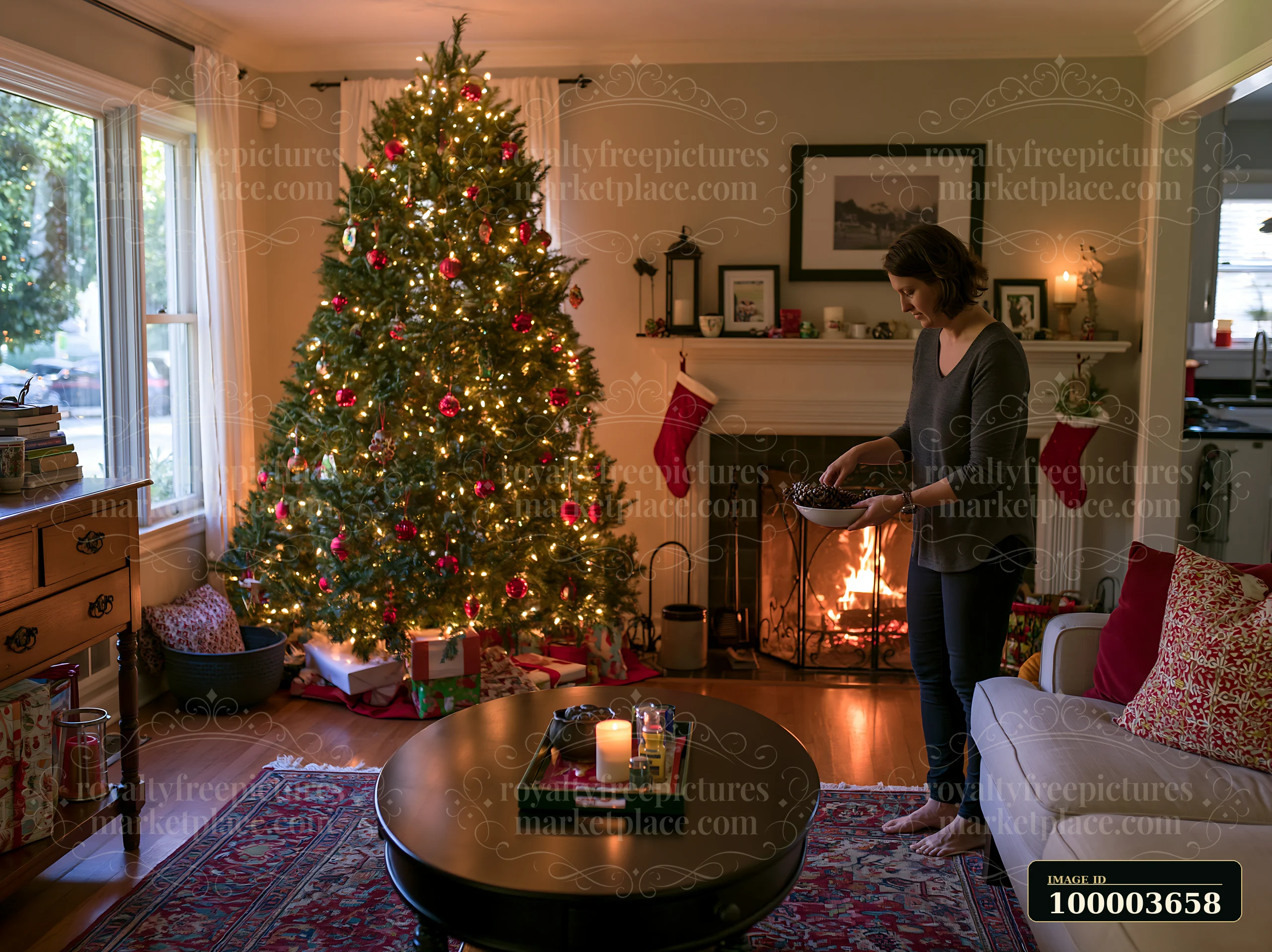 Woman holding a bowl beside a decorated Christmas tree and lit fireplace in a cozy living room.