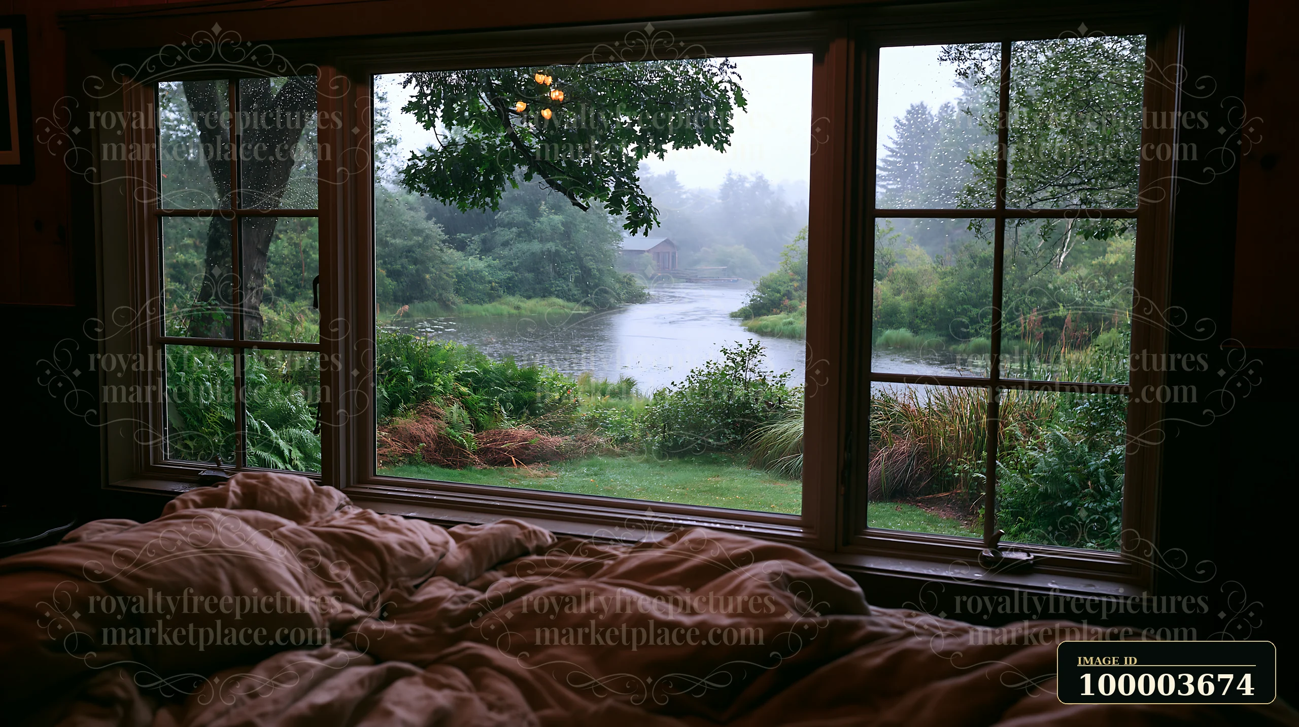 Rainy river landscape viewed through a timber cottage window above an unmade bed.