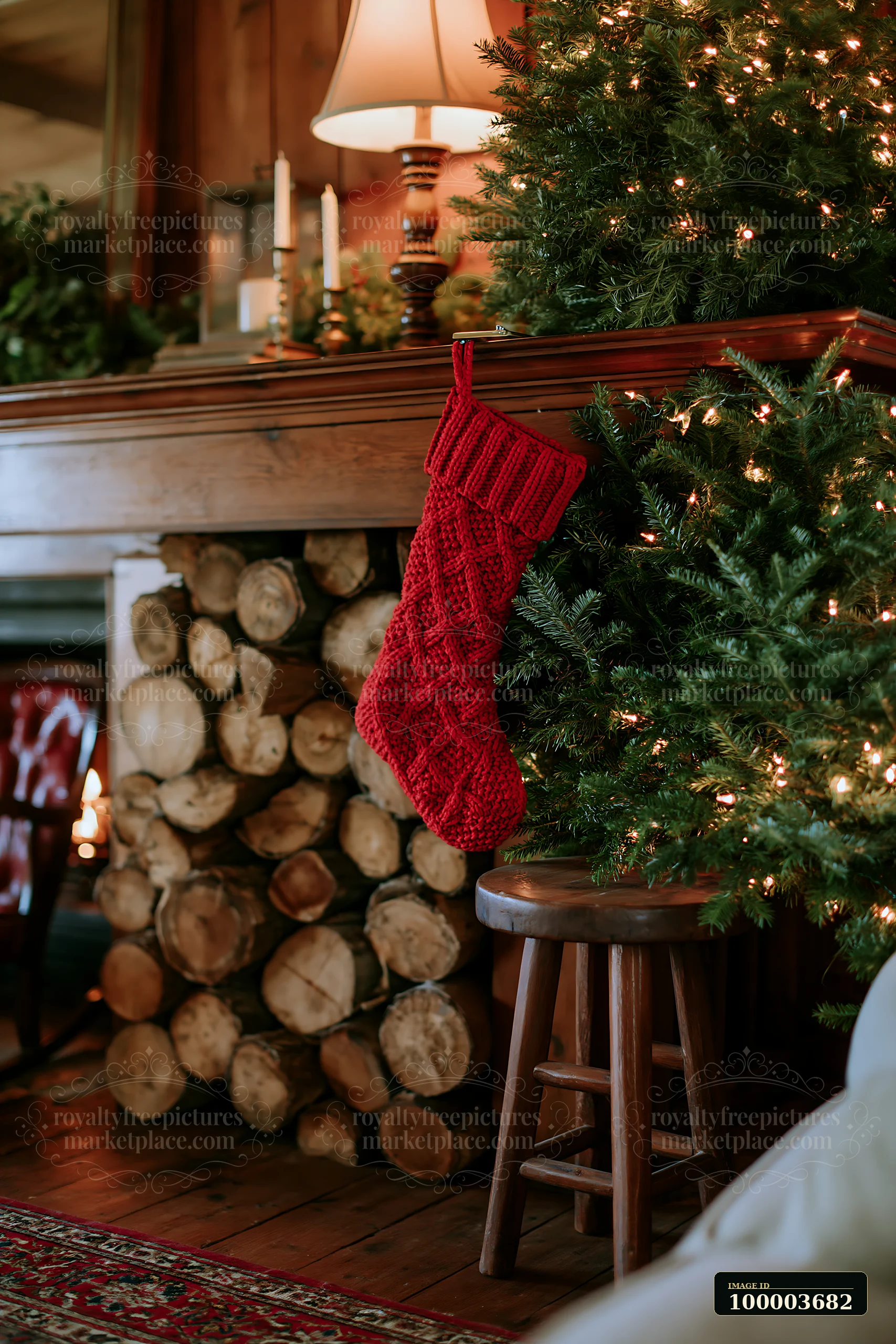 A red Christmas stocking hangs from a wooden mantle in a rustic home, with a Christmas tree adorned with lights and a wood pile nearby, creating a cozy holiday