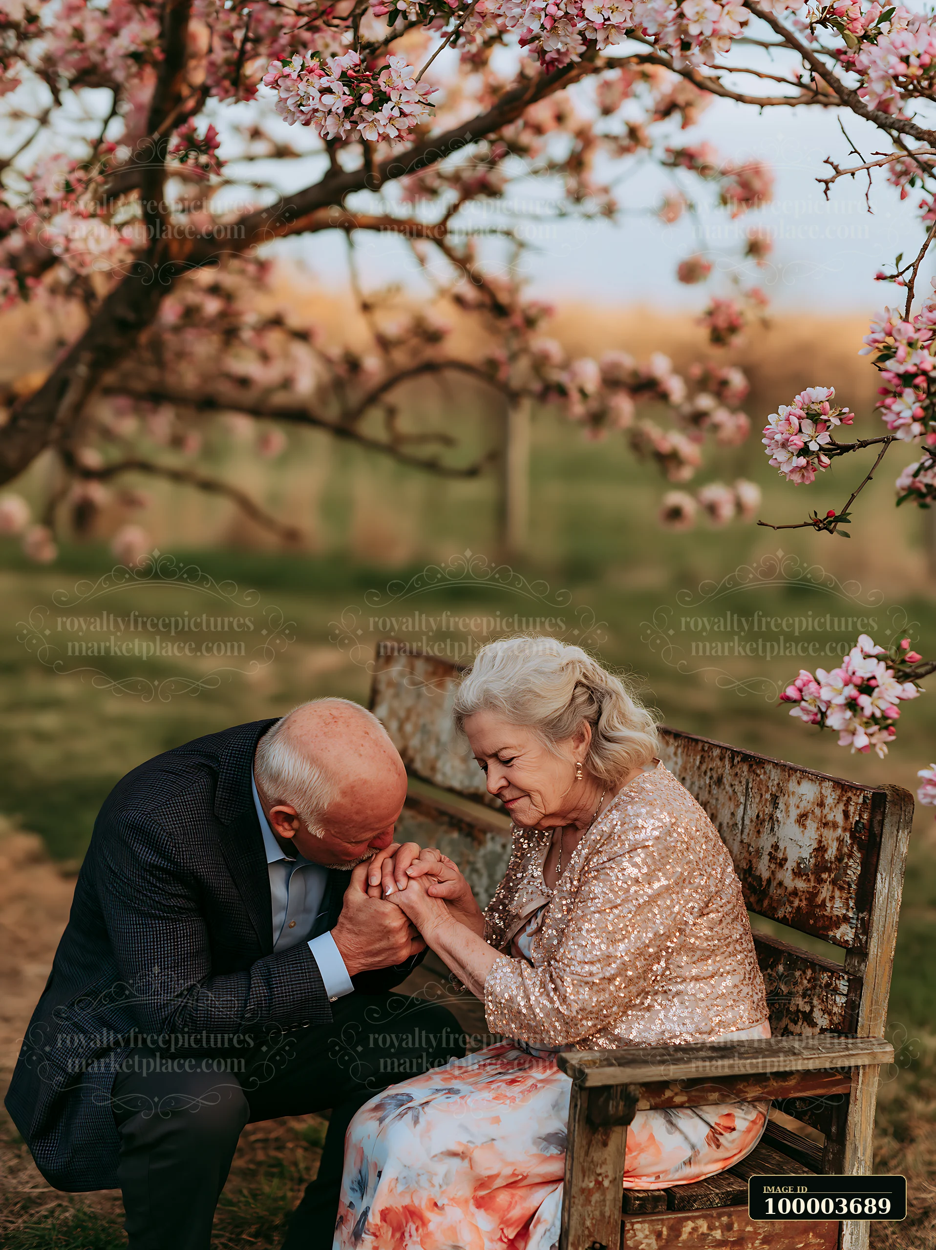 An elderly couple enjoys a gentle kiss on hand in a romantic garden.