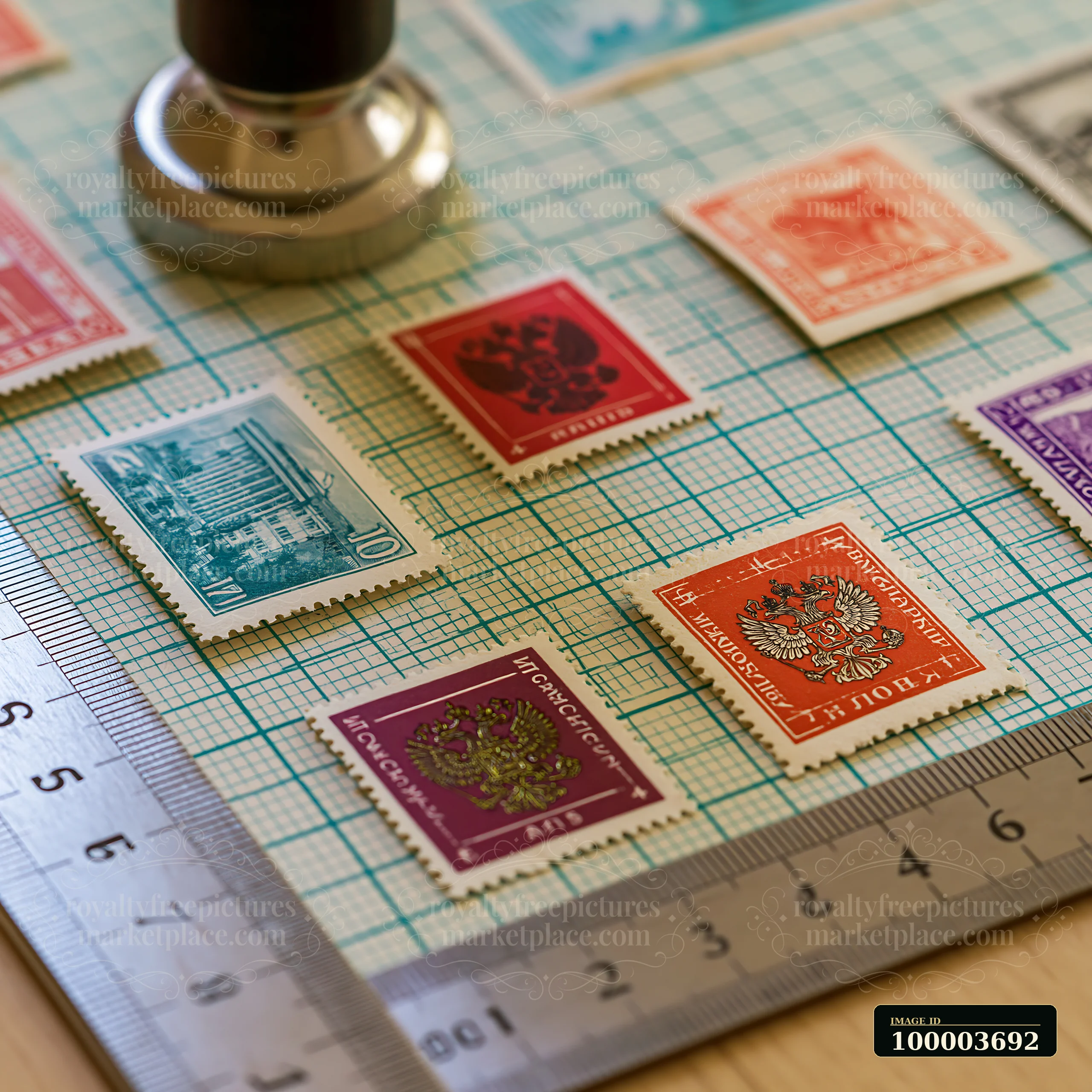 Soviet postage stamps are laid out on a grid surface next to a rubber stamp used for marking.
