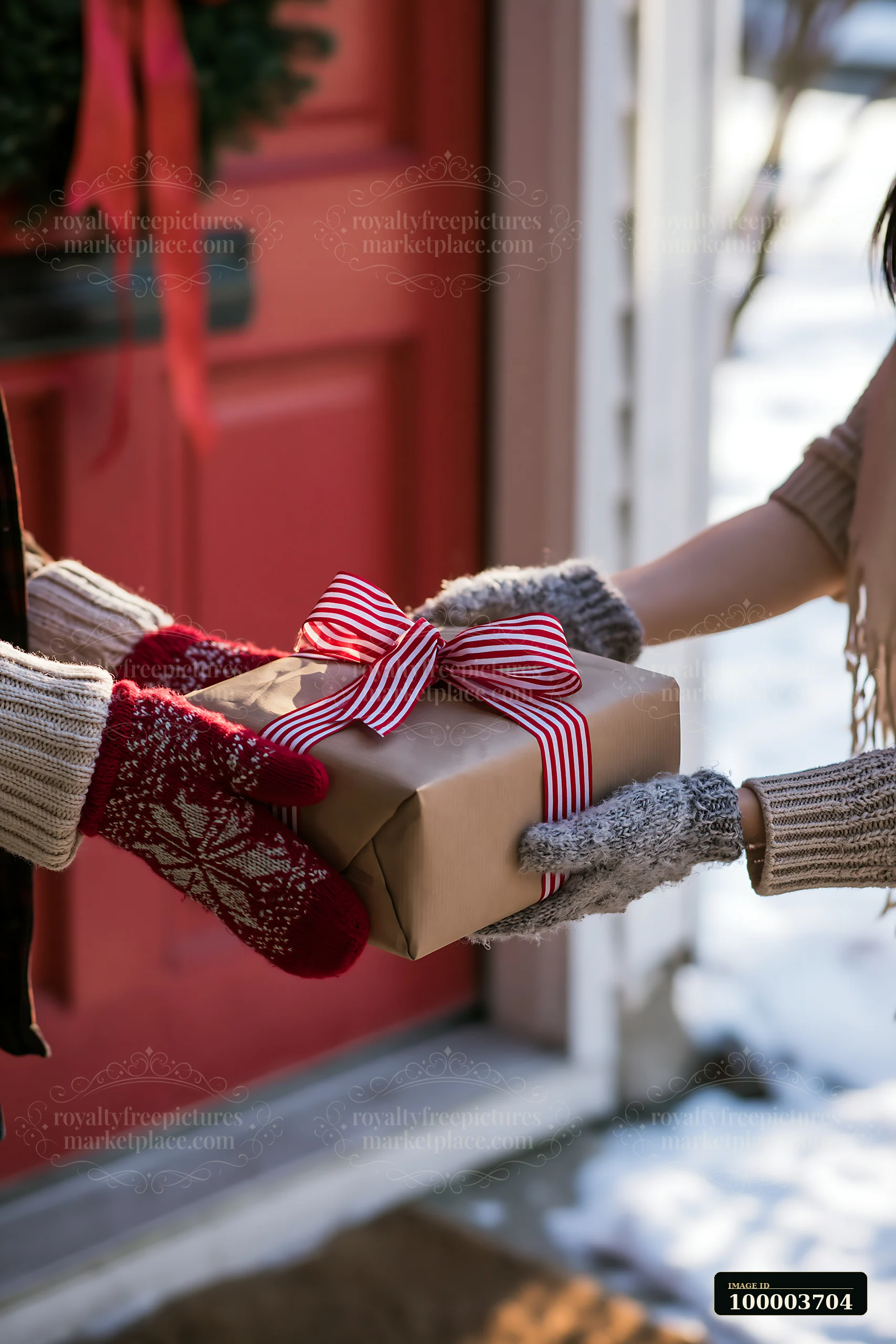 Gloved hands pass a wrapped present with a striped bow near a red doorway and snowy outdoors.