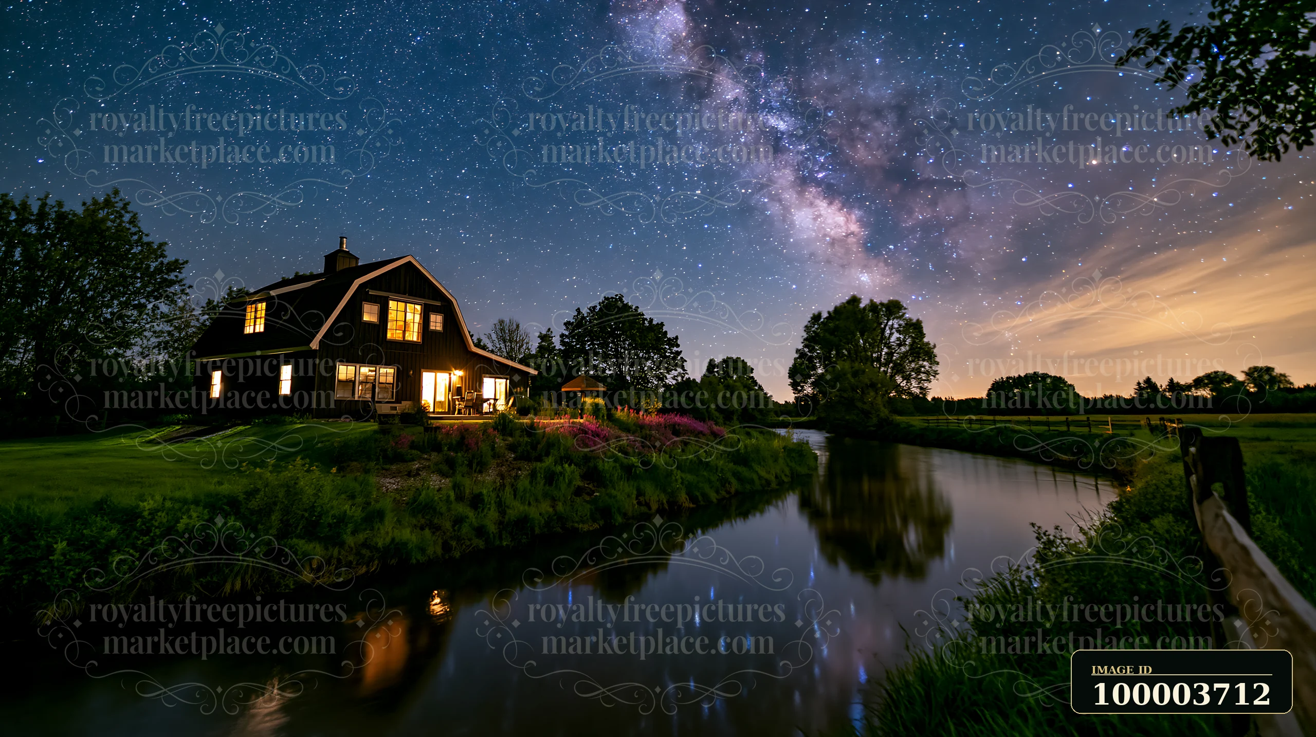 A modern house sits beside a river with bright lights.