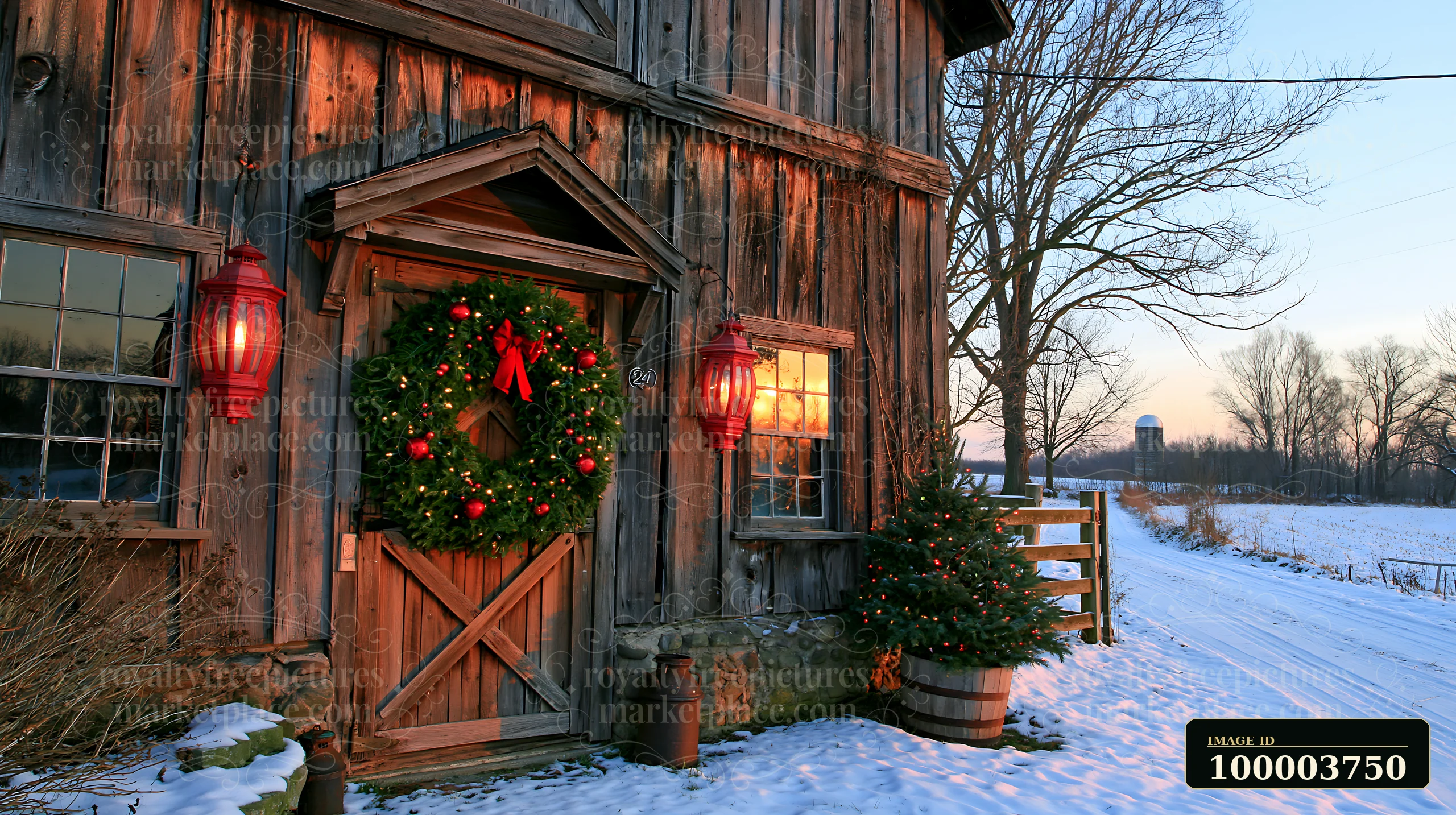 Snowy rustic farmhouse entrance decorated with a green wreath, red lanterns, and a lit Christmas tree.