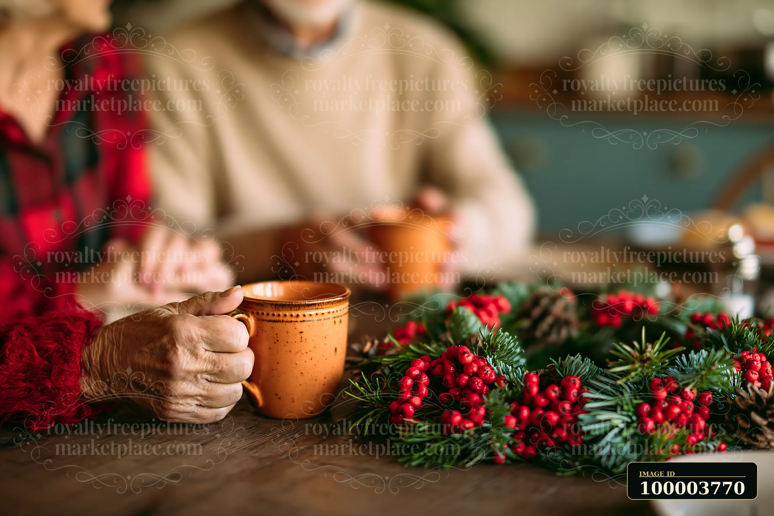 Two people hold mugs while sitting at a table decorated with a pine wreath and red berries.