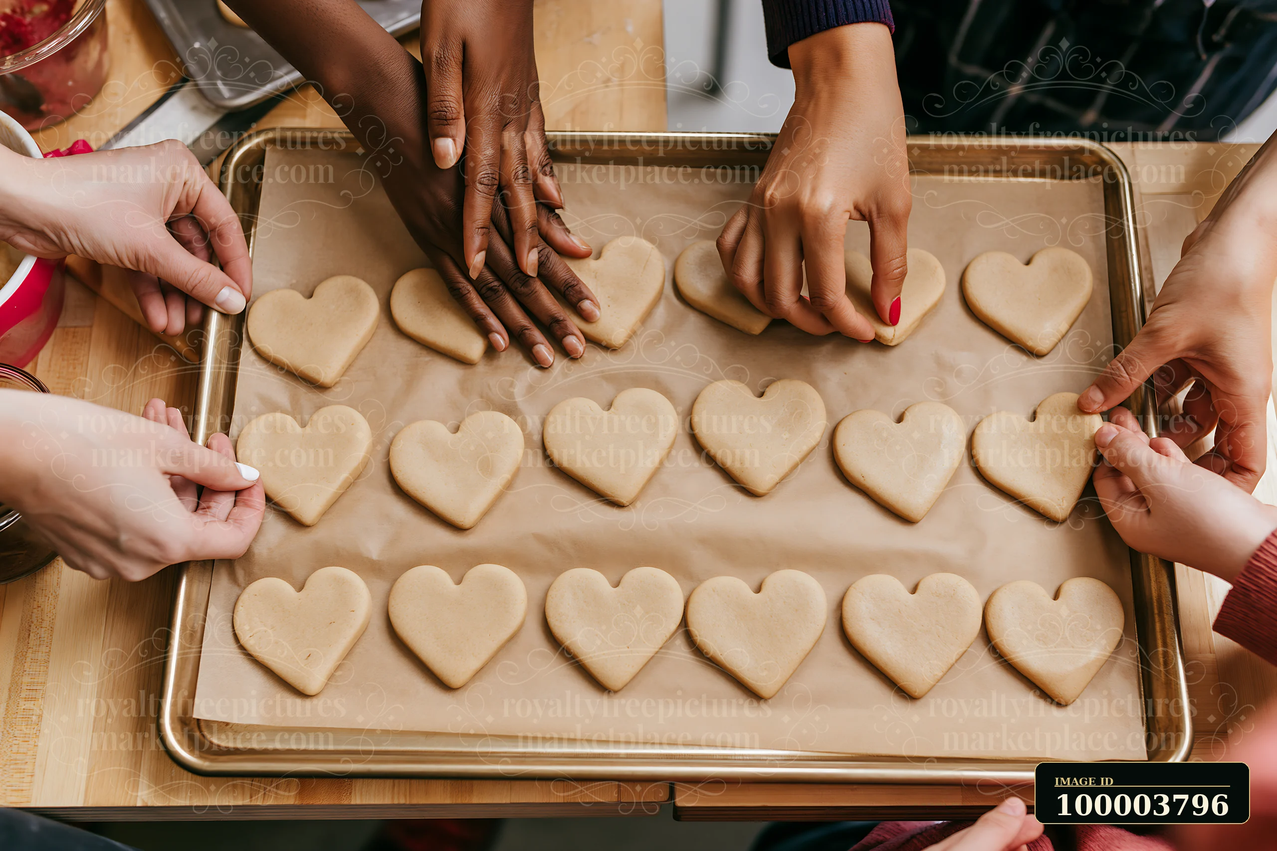 Hands of different people shape heart-shaped cookies on a baking tray at a kitchen counter.