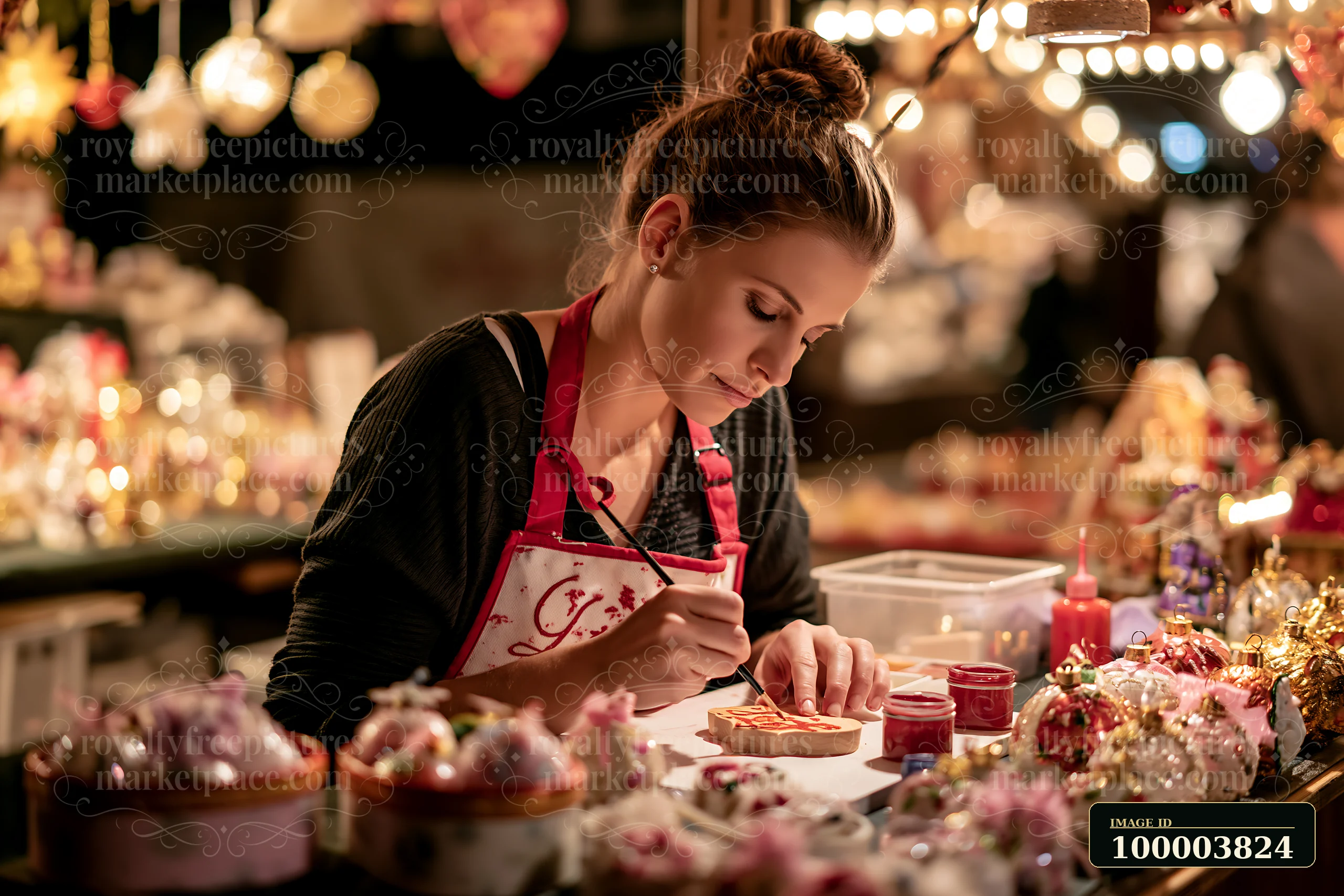 A woman paints ornaments at a Christmas market stall filled with handmade decorations.