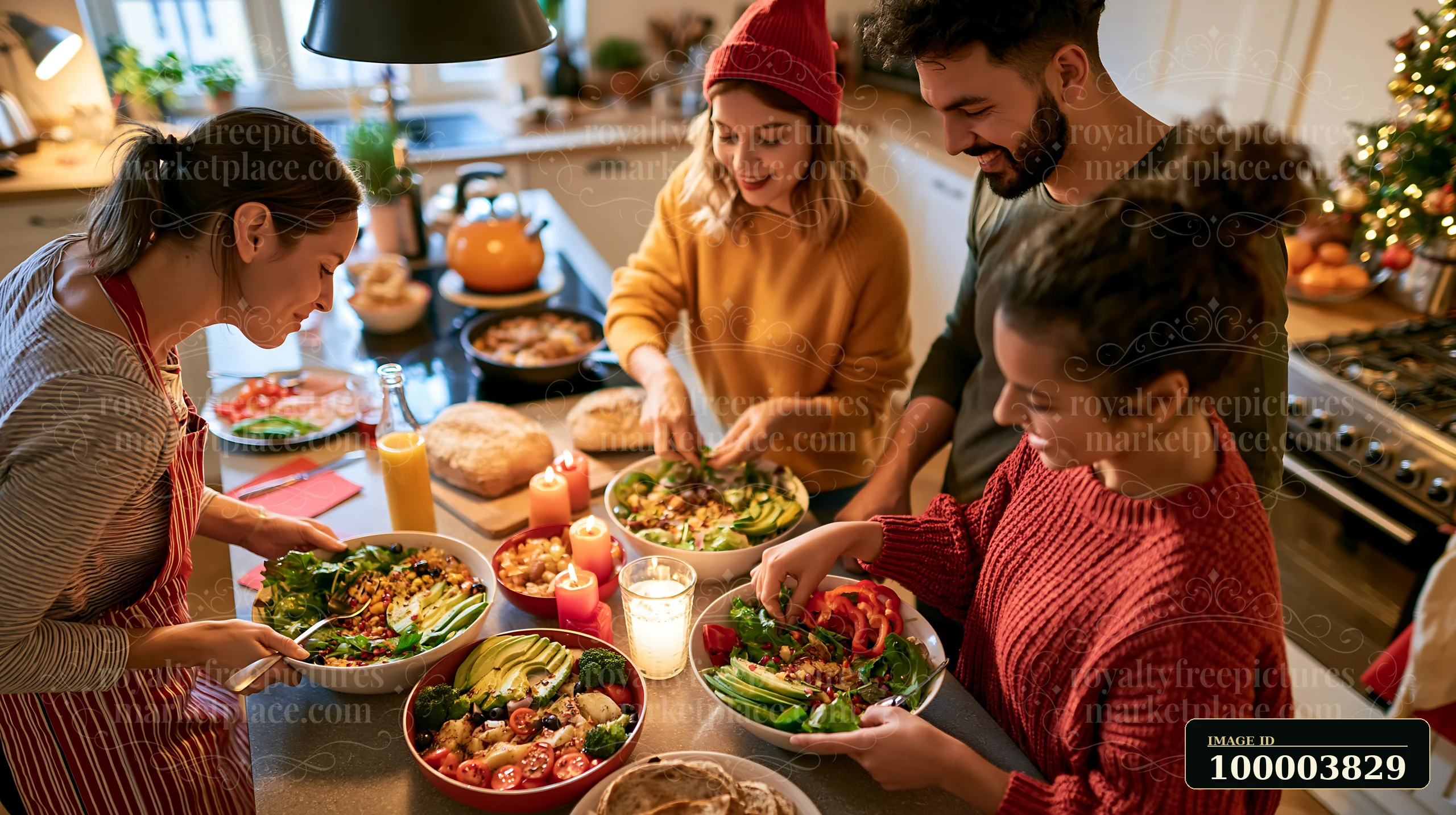 Four people prepare colorful salads and festive food around a kitchen island beside a decorated Christmas tree.