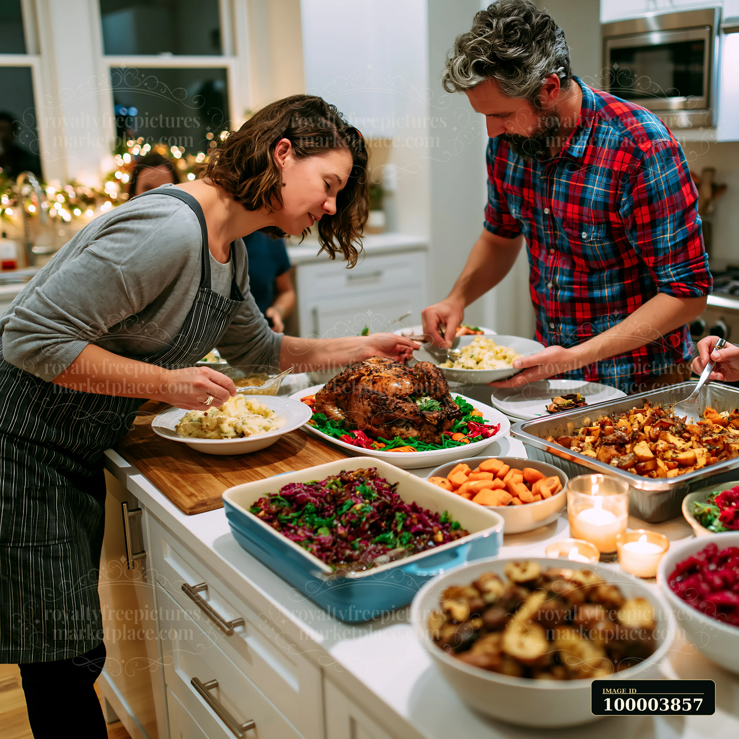 A man and a woman prepare plates with food from a holiday feast in a bright kitchen.