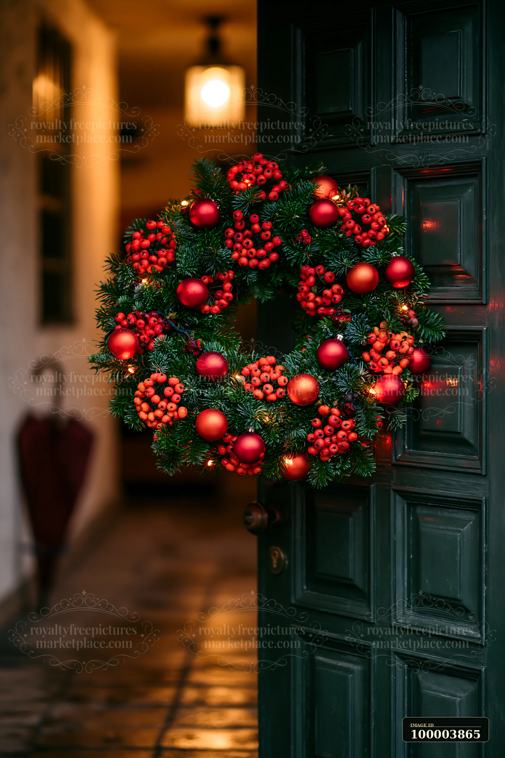 Decorated Christmas wreath with red berries and ornaments hangs on a dark apartment door.