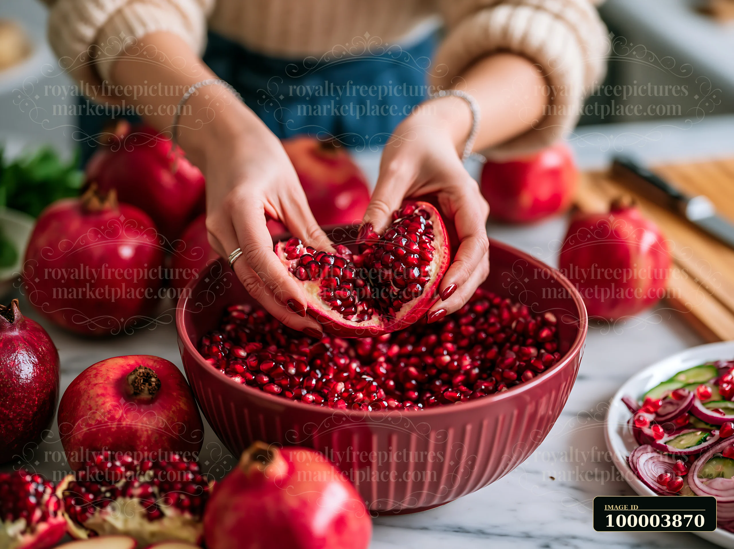 Hands remove seeds from a pomegranate above a bowl in a bright kitchen setting.