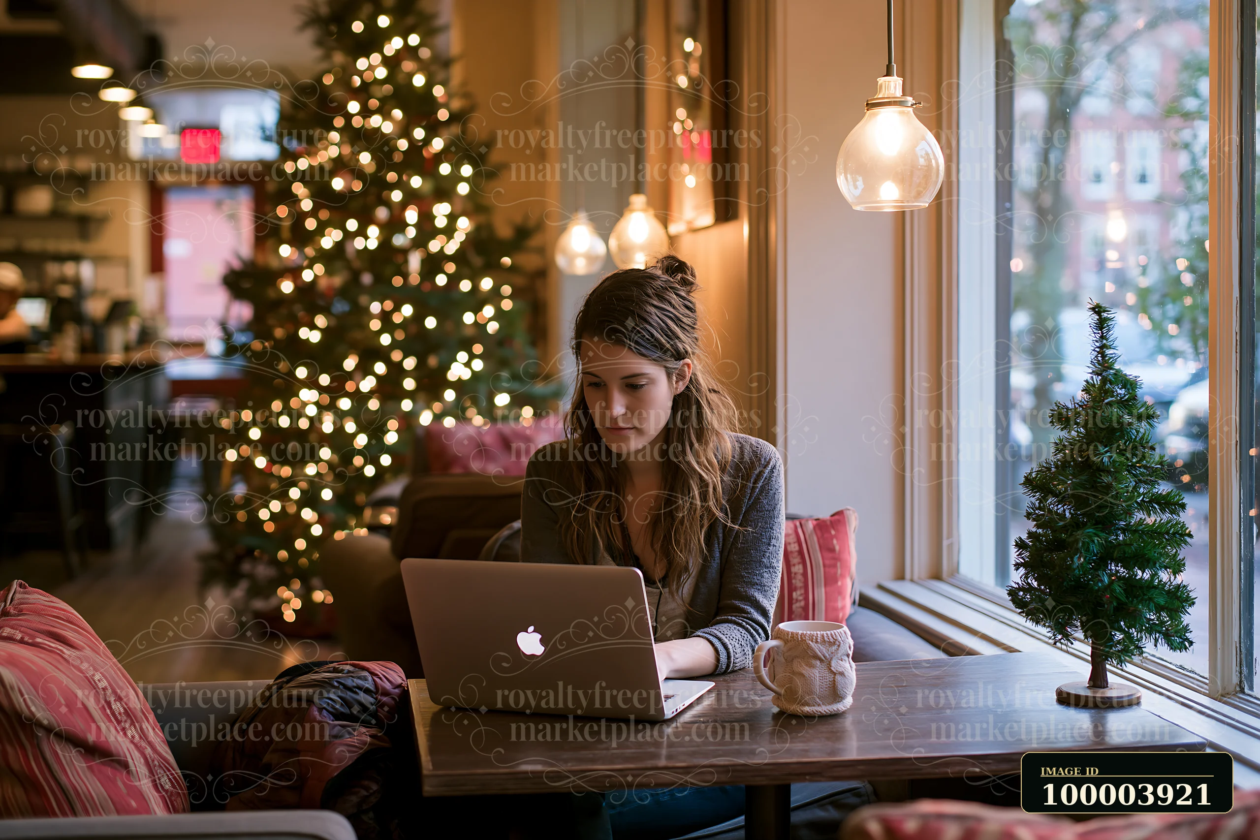 A woman works on a laptop at a cozy coffee shop with holiday decorations.