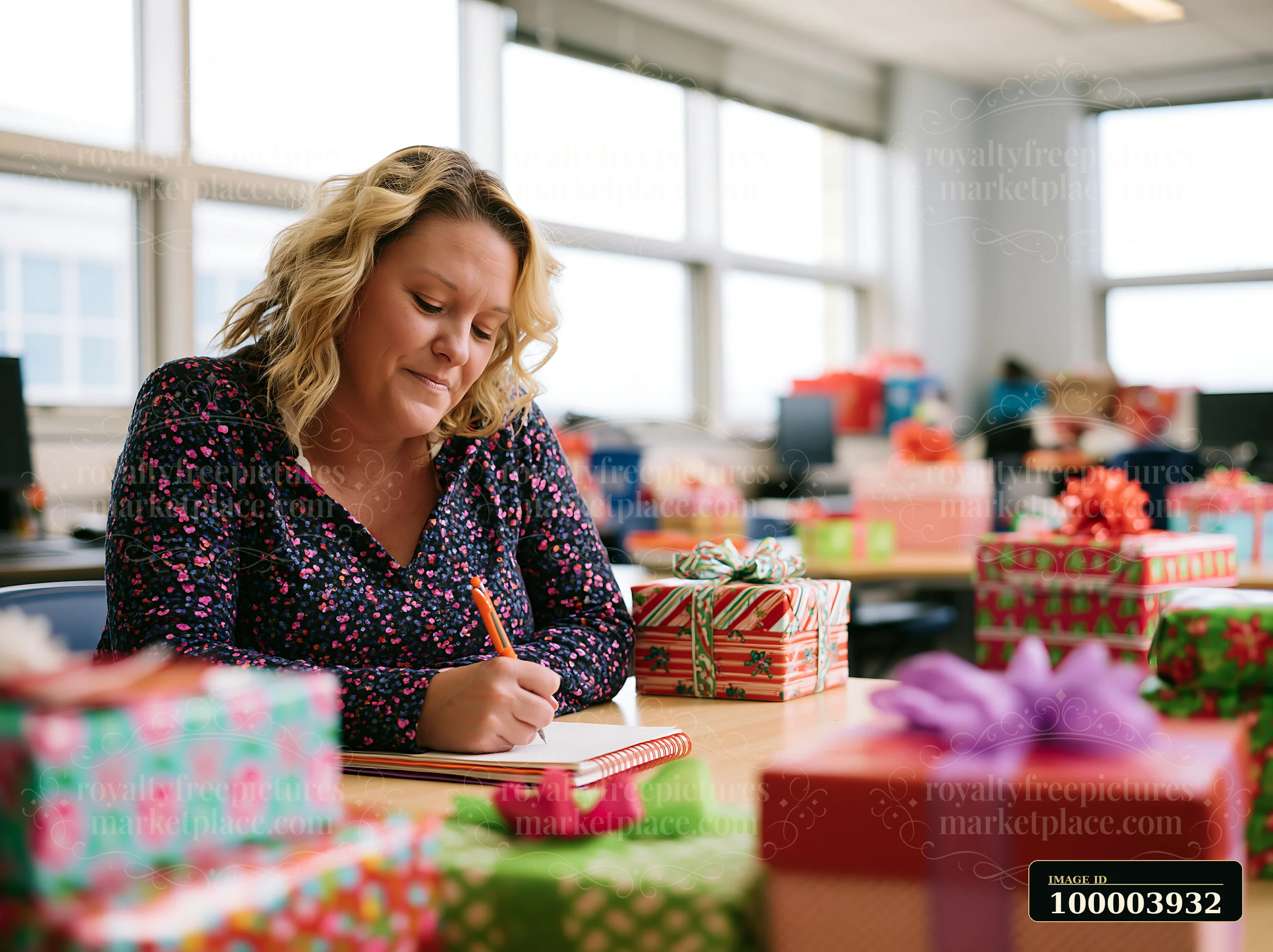 A woman is sitting at a desk in a room filled with wrapped gifts.